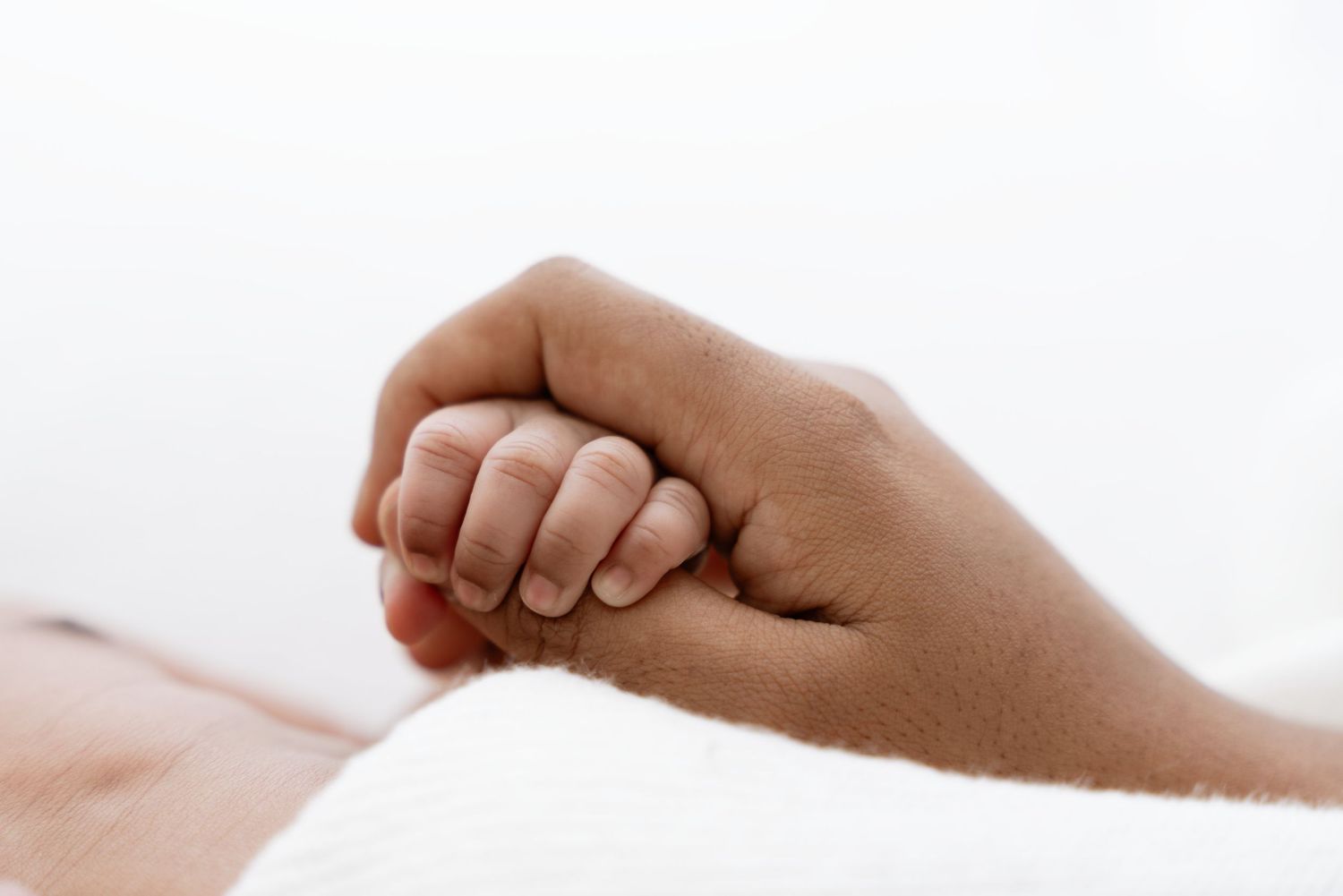 Close up black and white photo of a baby's tiny fingers against a white background.
