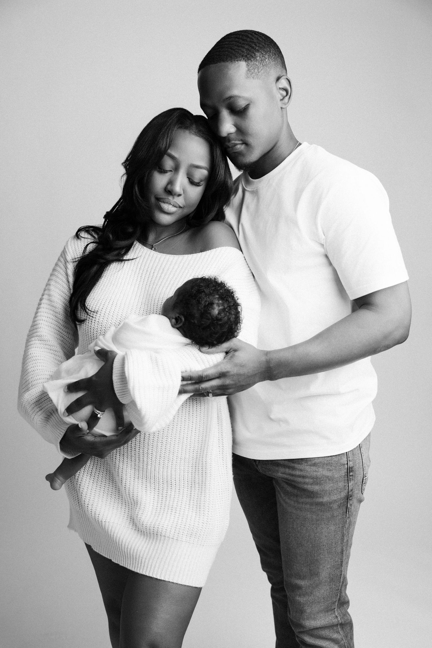 Black and white photo showing tender moments between a parent and child in matching white tops captured by a Michigan newborn photographer.
