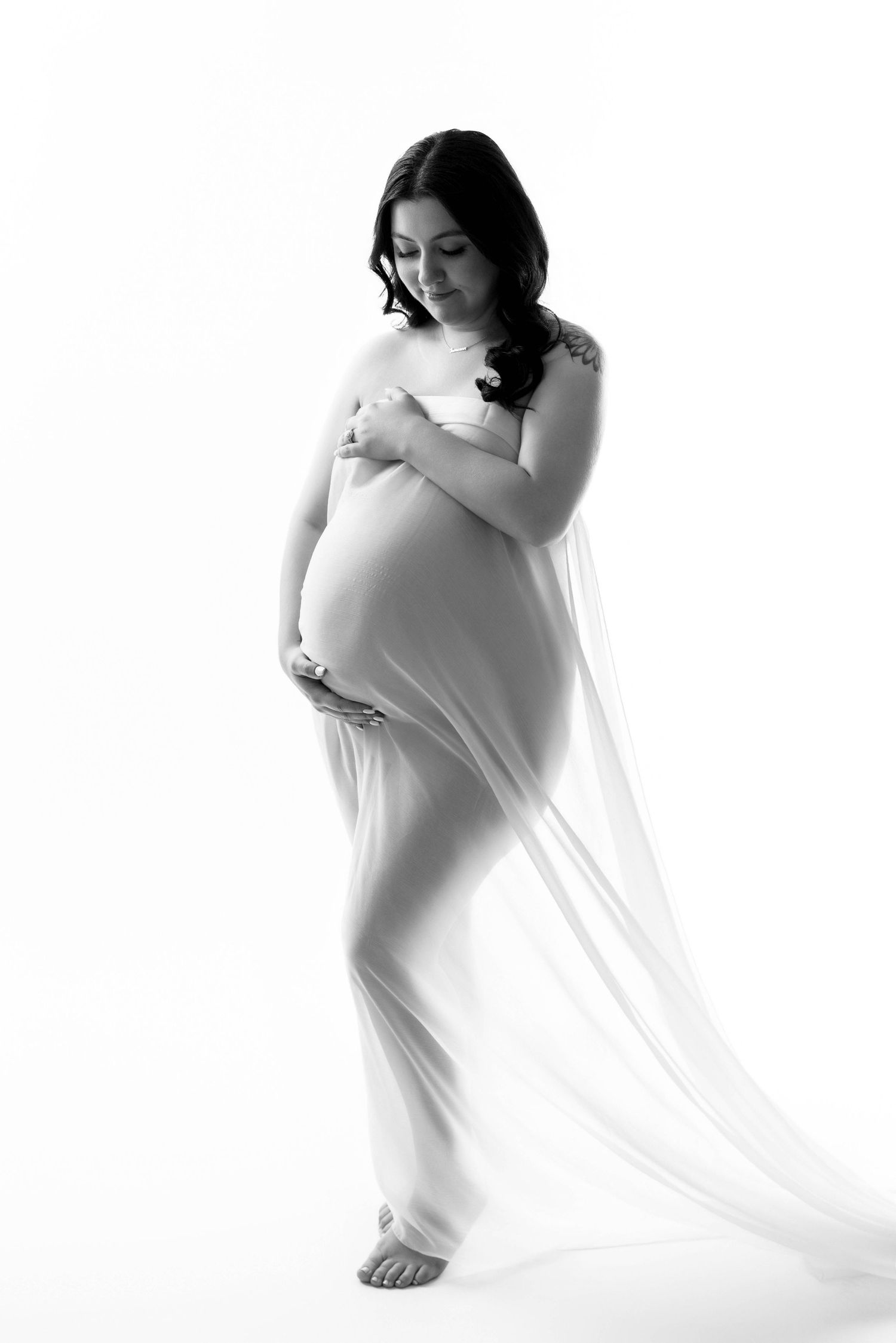 Ethereal maternity portraits with flowing white fabric against bright studio backdrop.