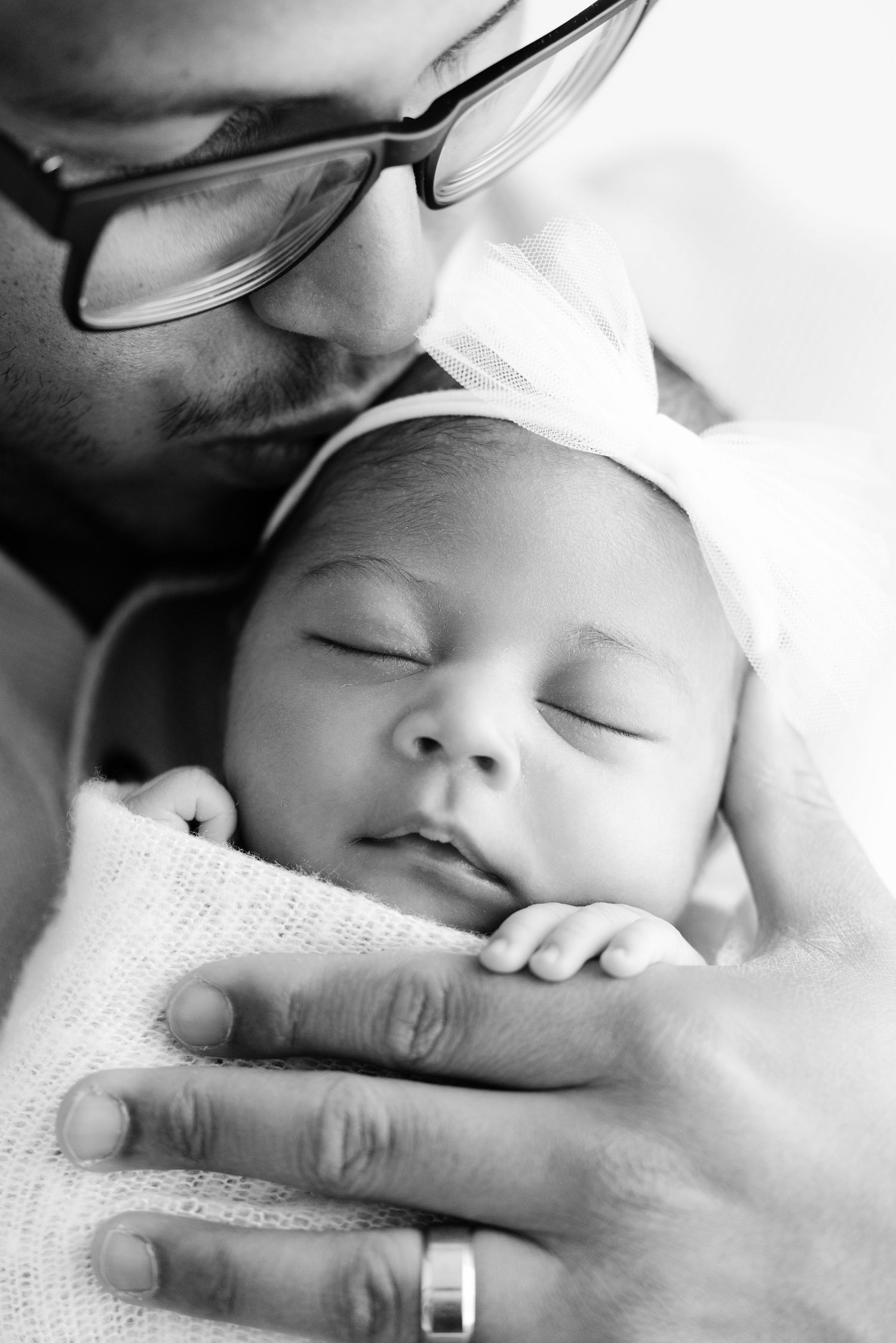 Black and white close-up photos showing gentle hands cradling sleeping newborn.