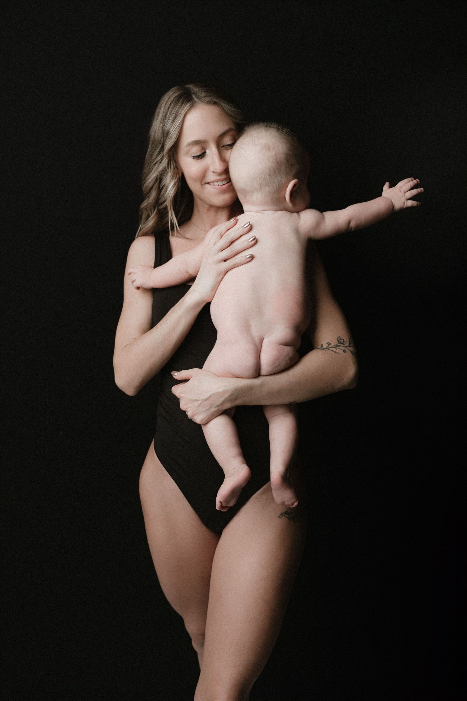 A series of intimate black and white portraits showing tender moments between mother and baby against dark background.