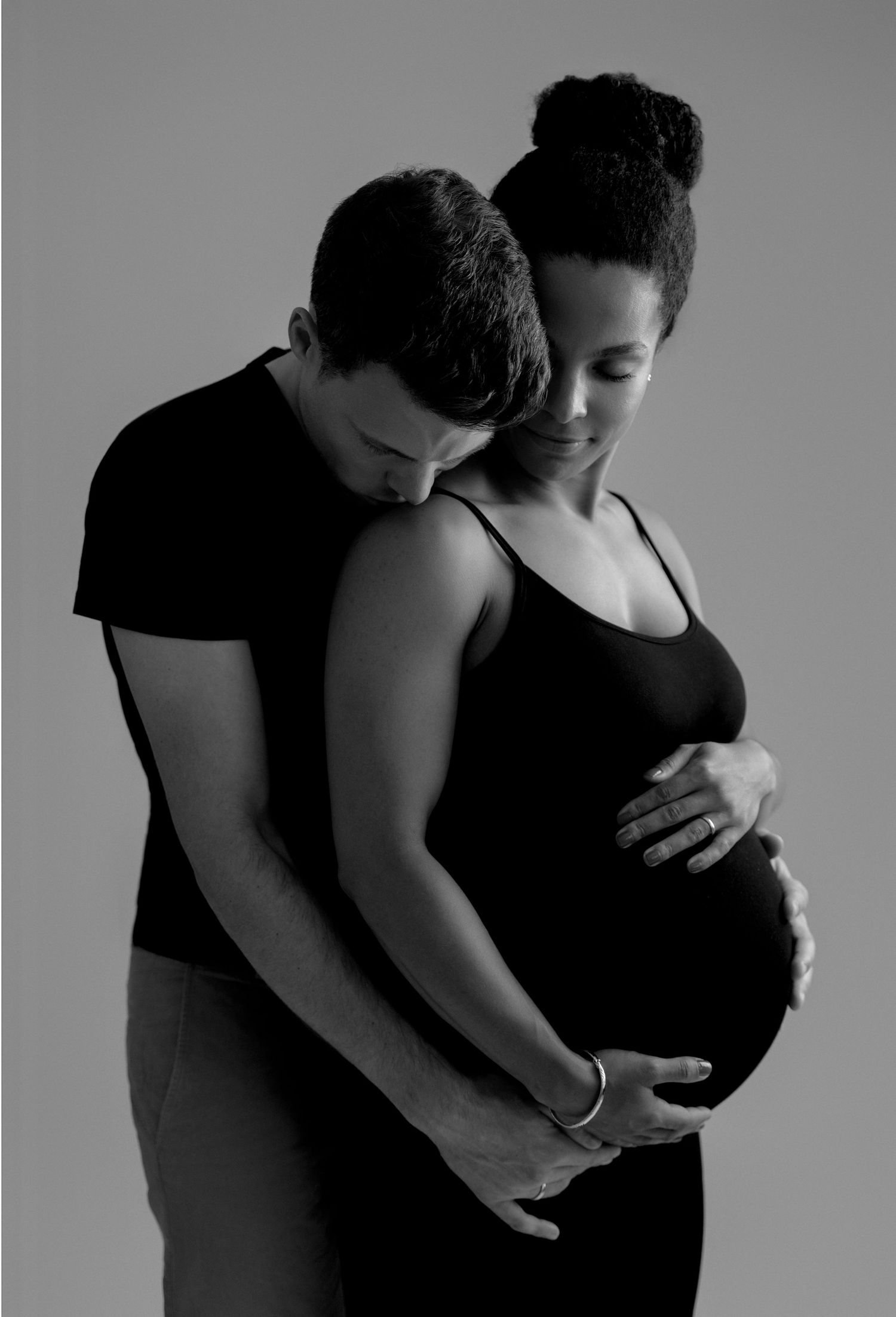 Black and white series of intimate pregnancy portraits showing a couple embracing and cradling a pregnant belly.