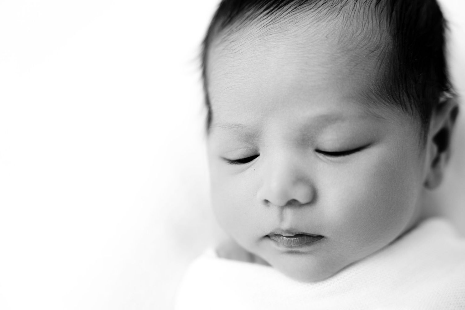 Black and white closeup of a sleeping baby's features in a minimalist style.
