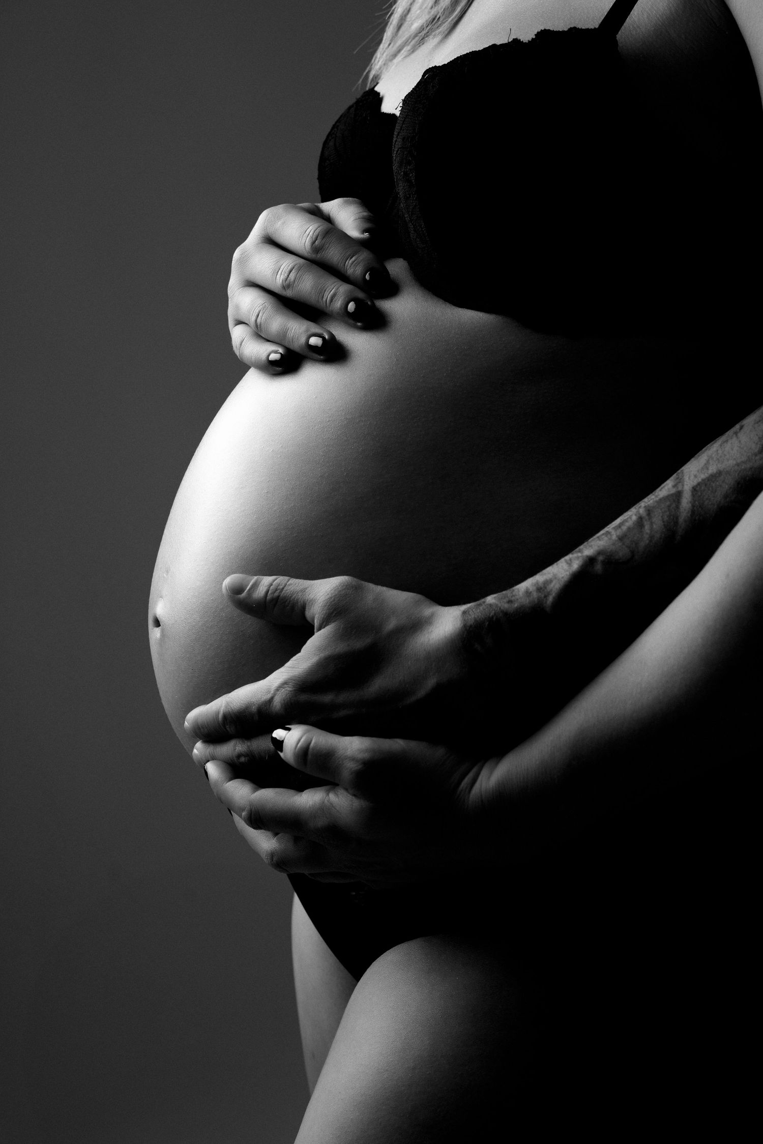 Dramatic black and white close-up photos of hands cradling pregnant belly.