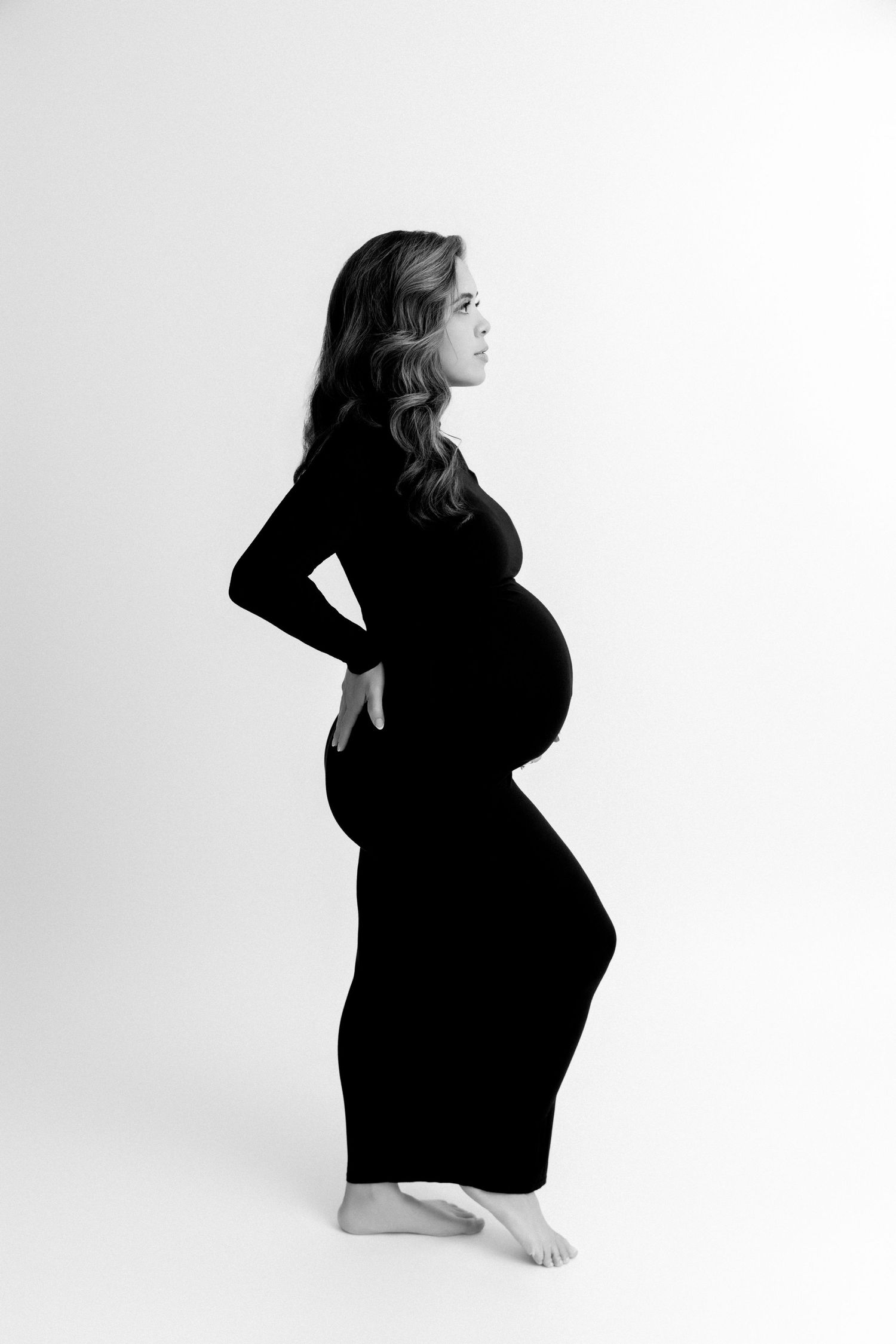 Silhouetted maternity poses in black dress against white background showing pregnancy progression.