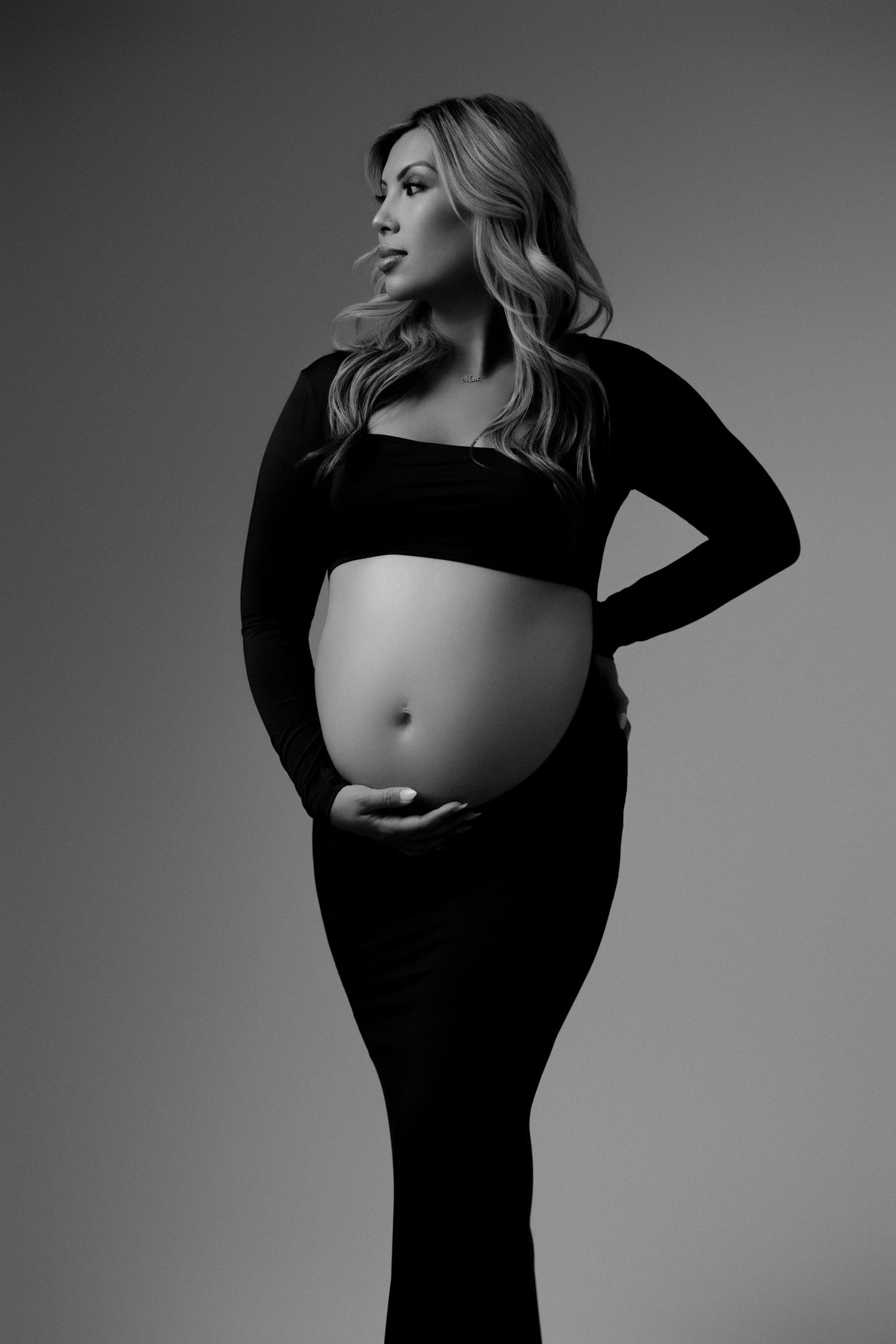 Artistic black and white maternity photos showing pregnant woman in dark clothing.