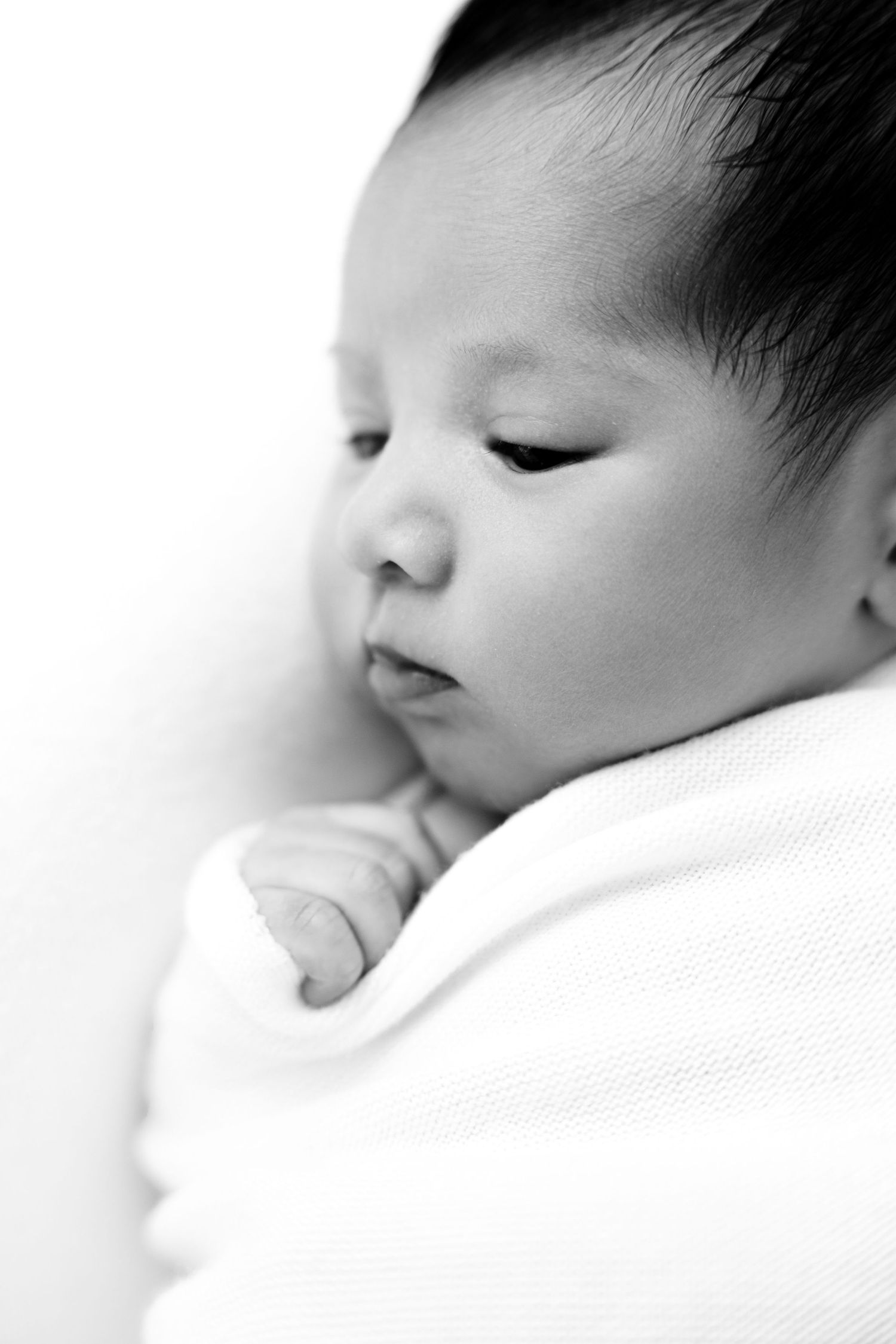 Peaceful side profile portraits of sleeping newborn in soft monochrome tones.