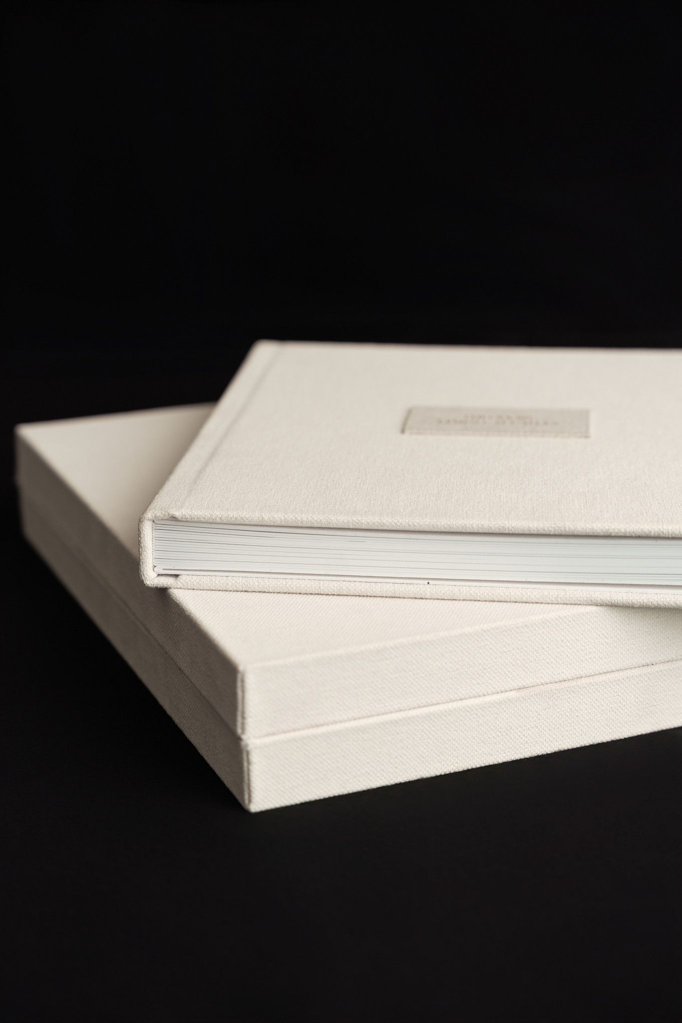 Two white hardcover books stacked on a black background with minimalist design and clean edges.