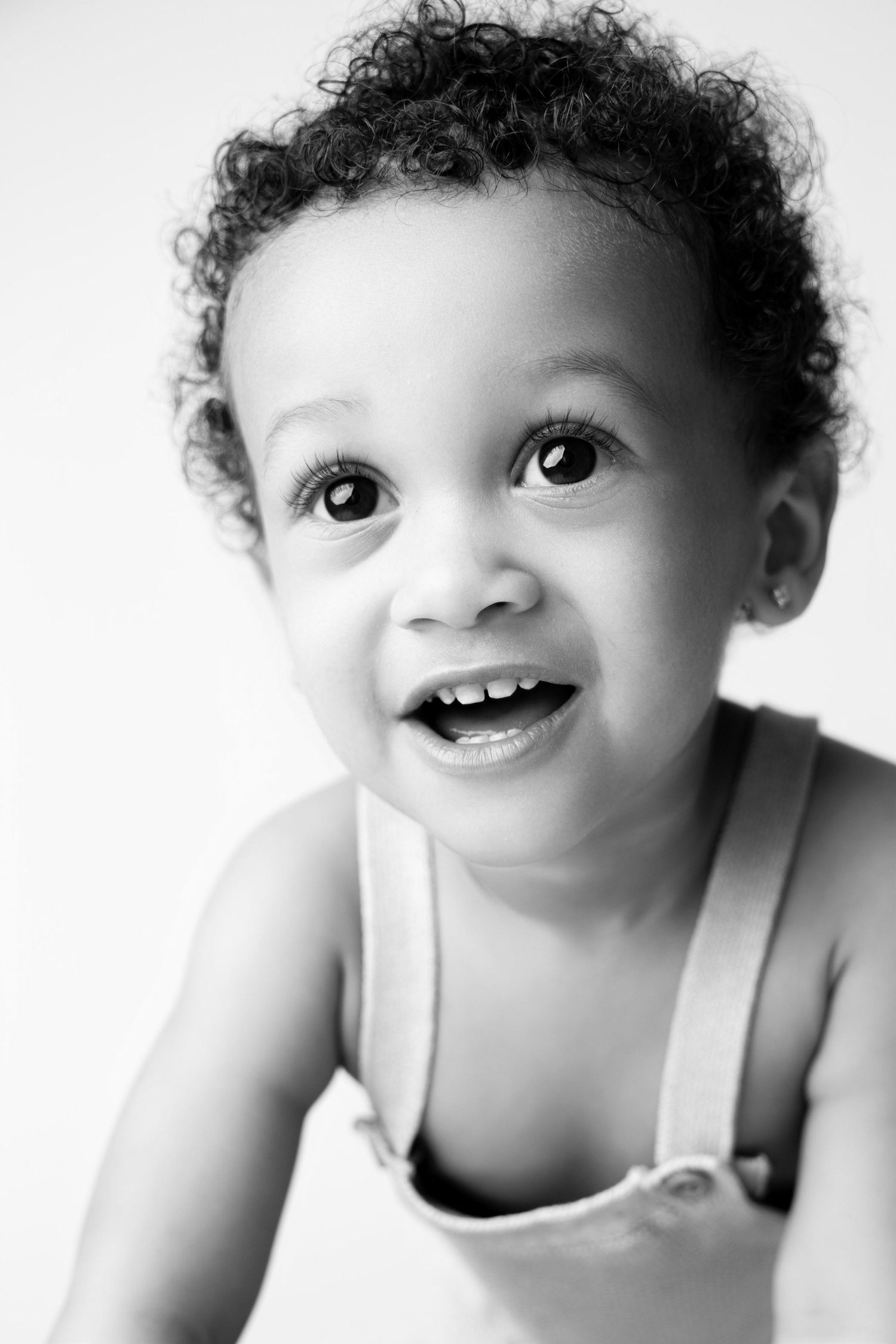 Black and white portrait series showing a baby's joyful expressions and curly hair against a white background.
