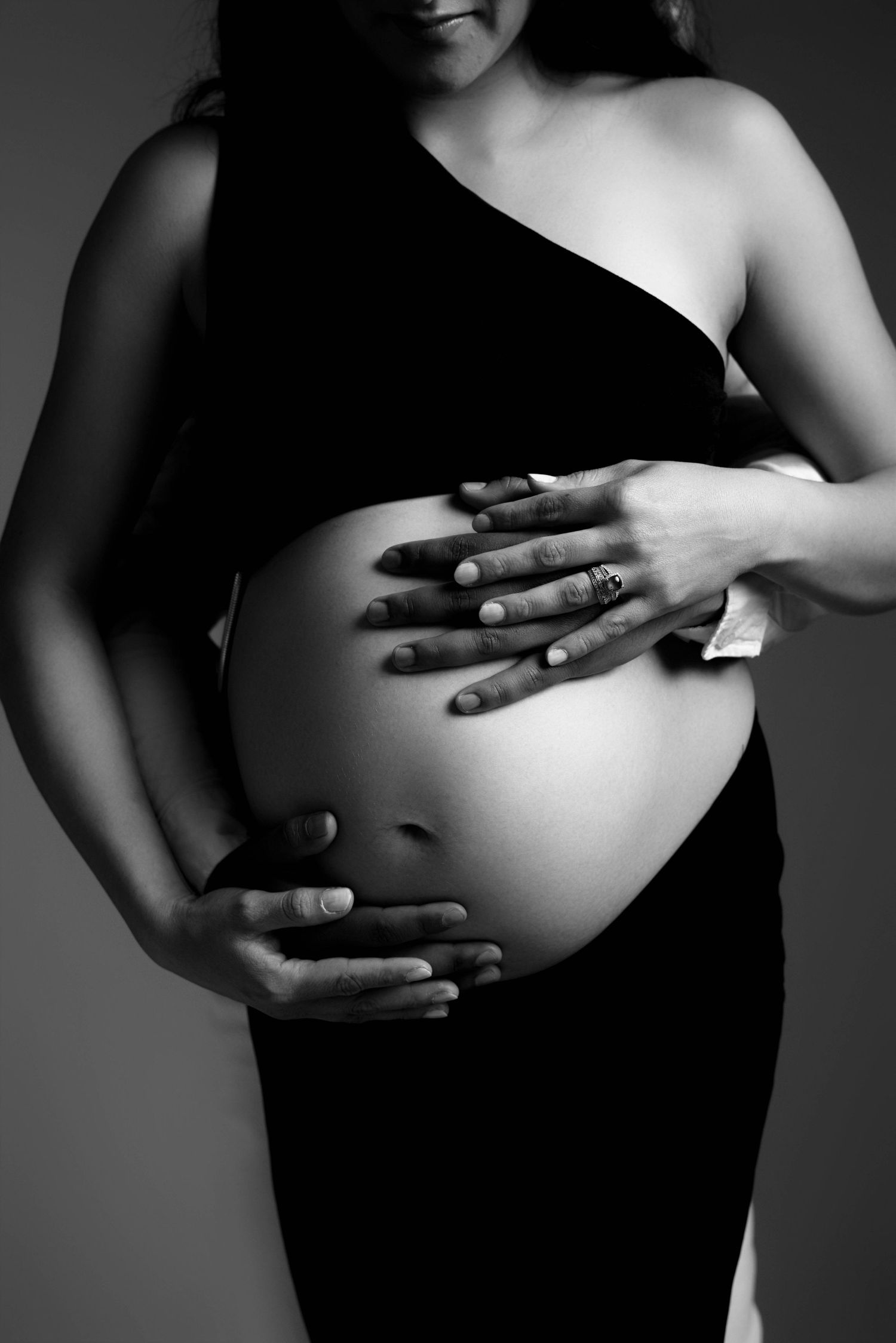 Black and white pregnancy photo series showing hands cradling baby bump.