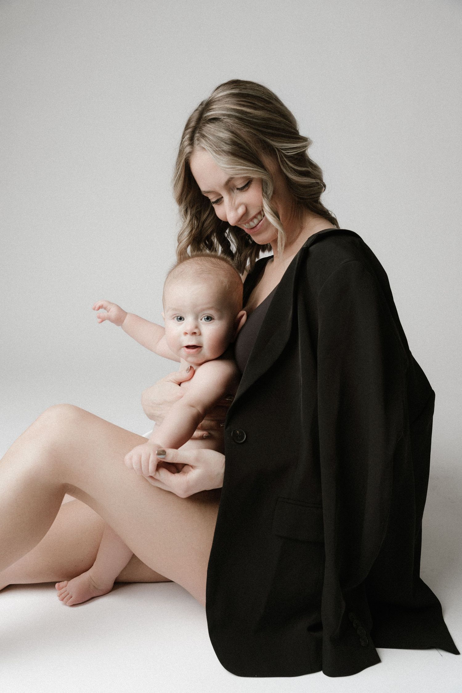 A series of tender black and white studio portraits showing intimate moments between parent and baby on light background.