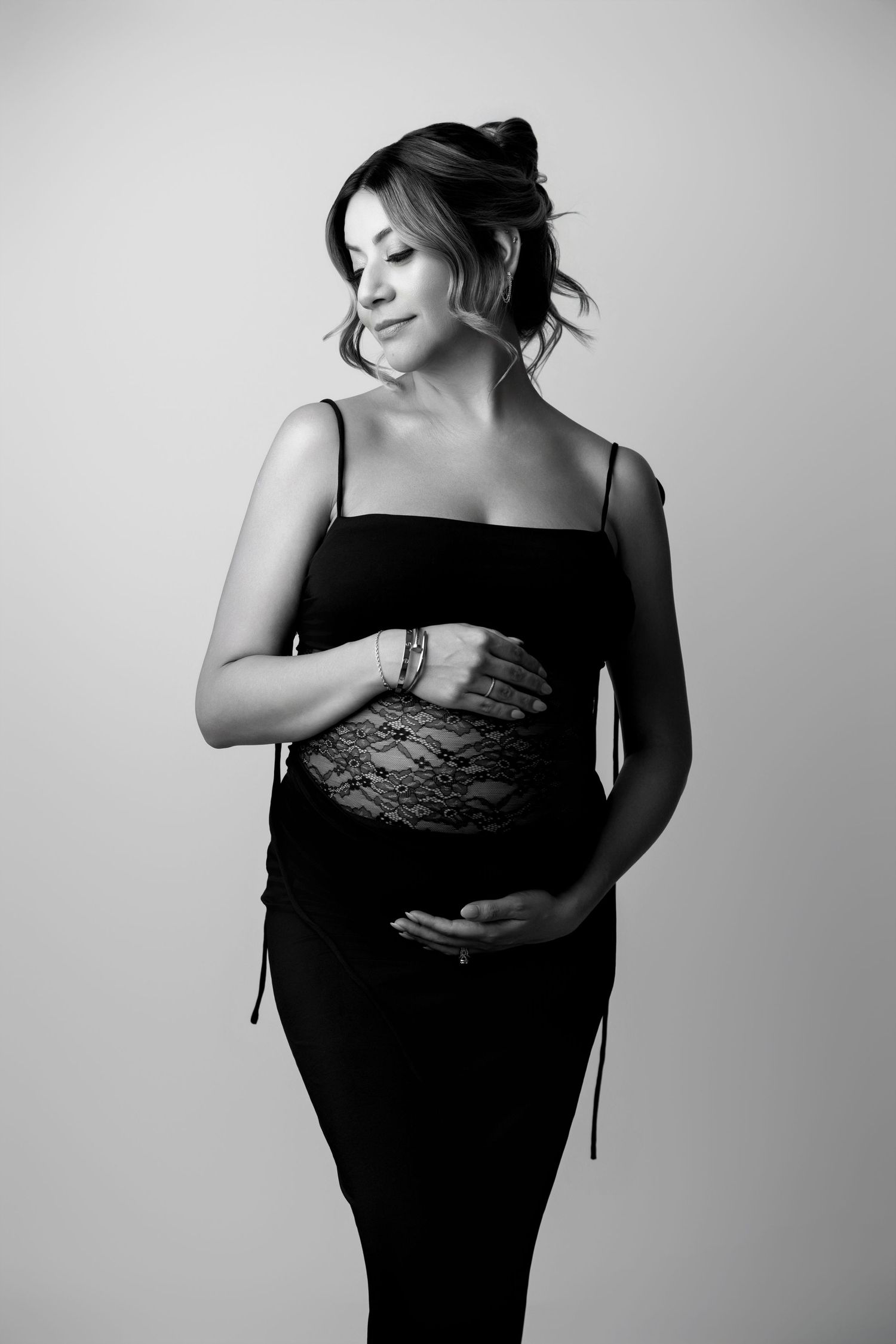 Elegant maternity photos in black dress showing silhouette against light background.