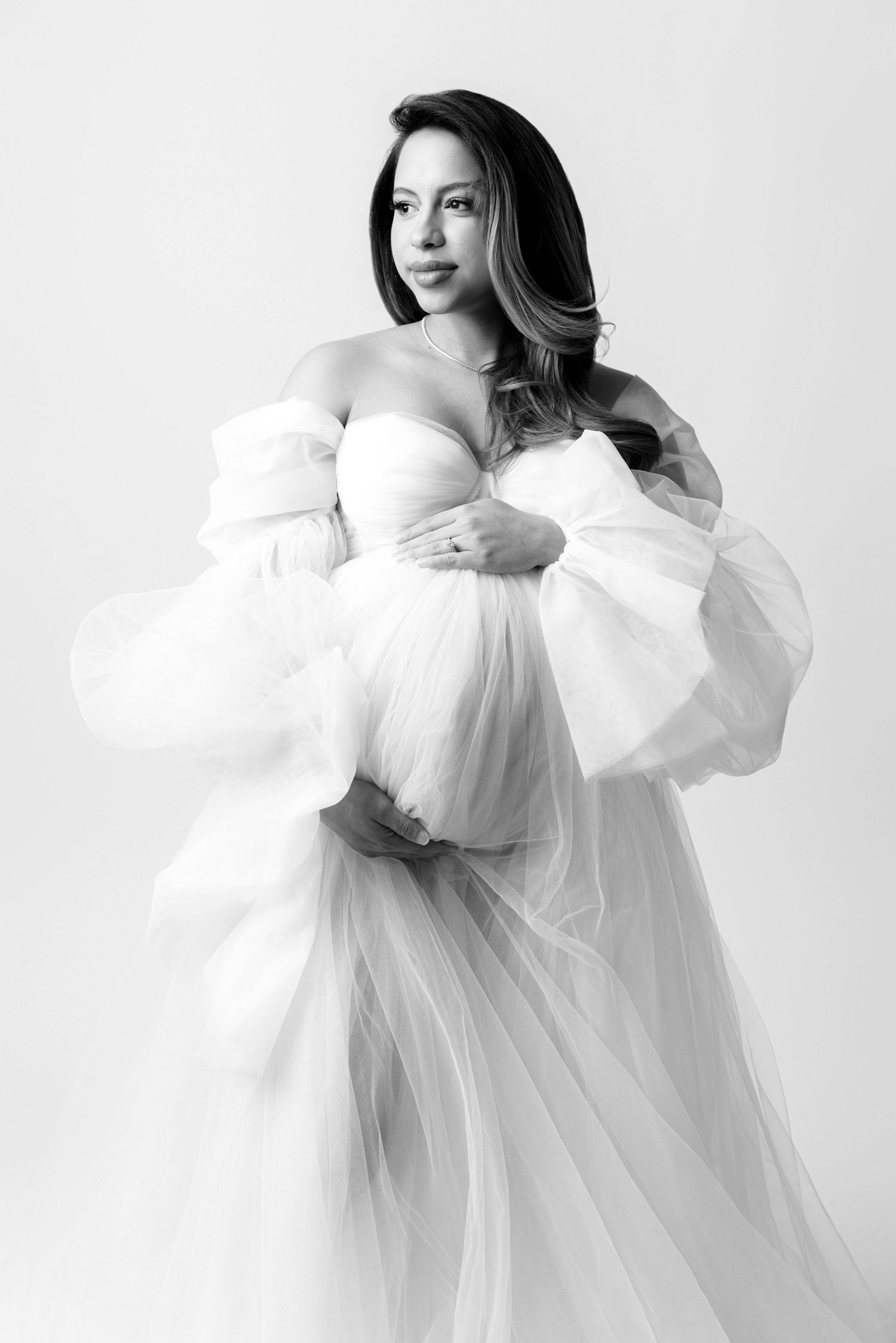 Ethereal portrait series in white featuring flowing tulle dress against bright studio backdrop.