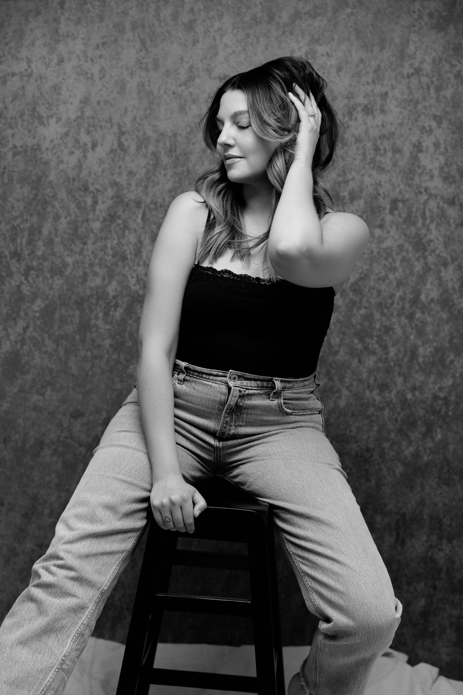 Artistic black and white portrait series against textured background showing casual poses.