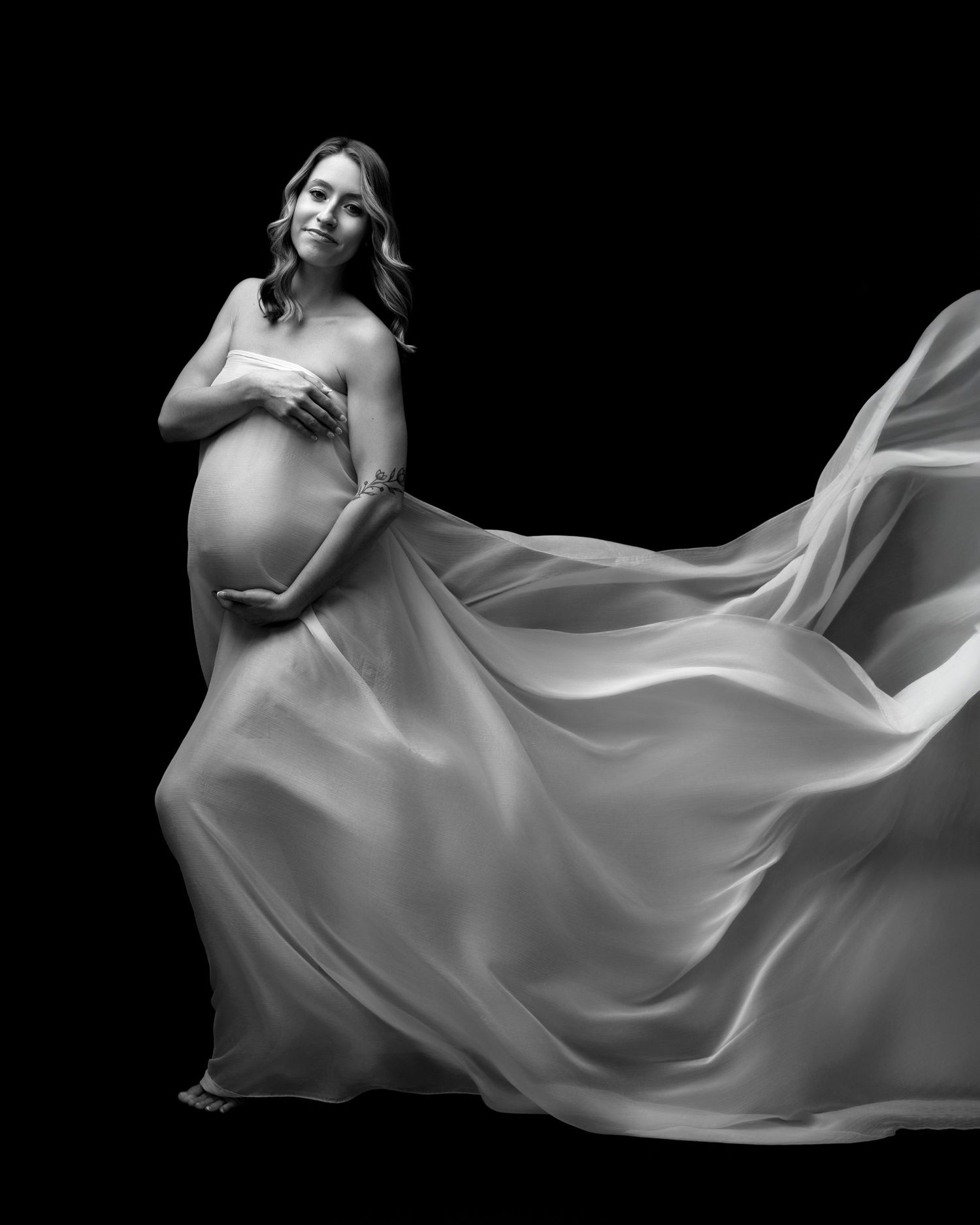 Artistic black and white photo of a pregnant women with flowing dress captured by a Michigan maternity photographer.