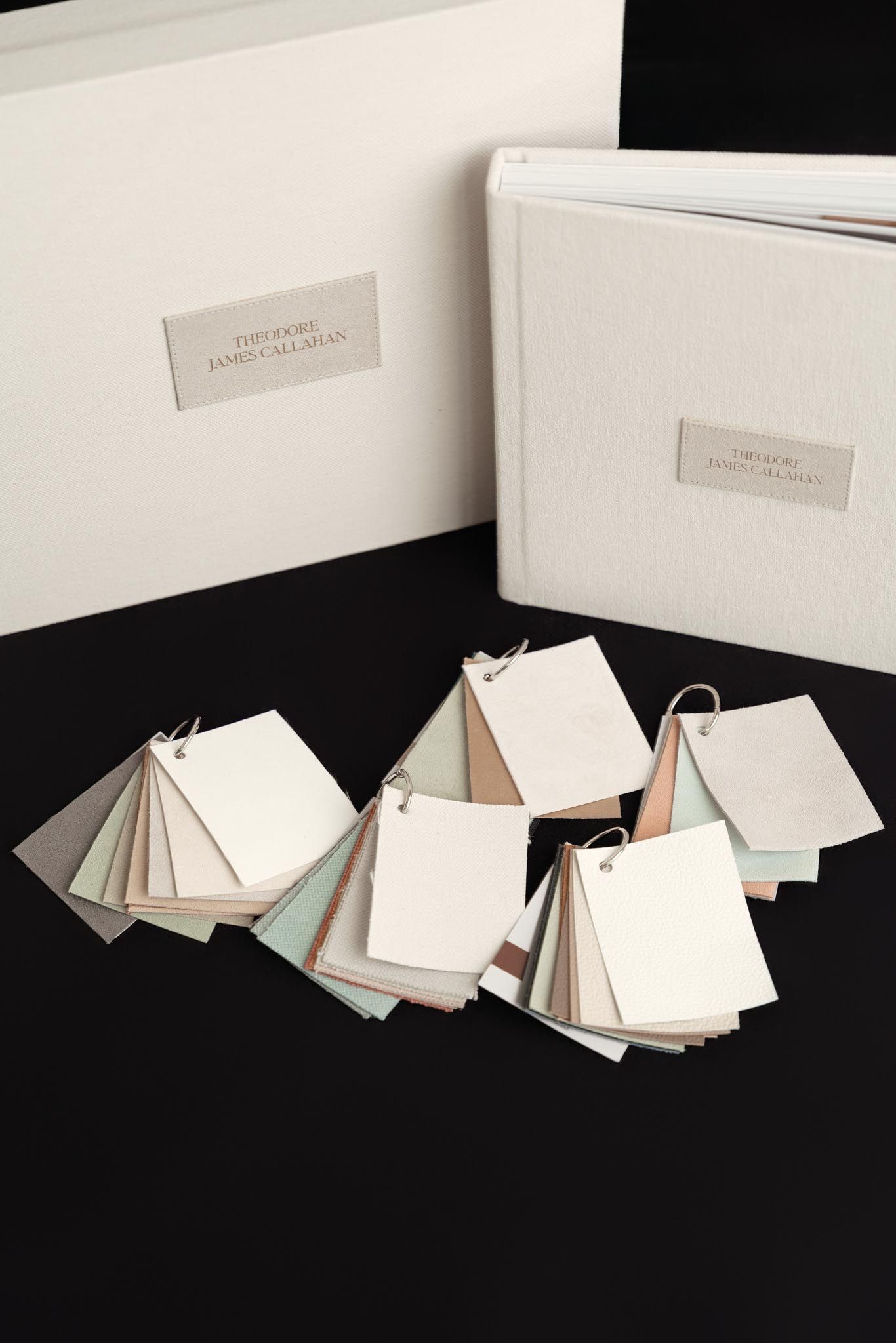 White paper sample books and swatches arranged on black surface with labeled binders for material selection.