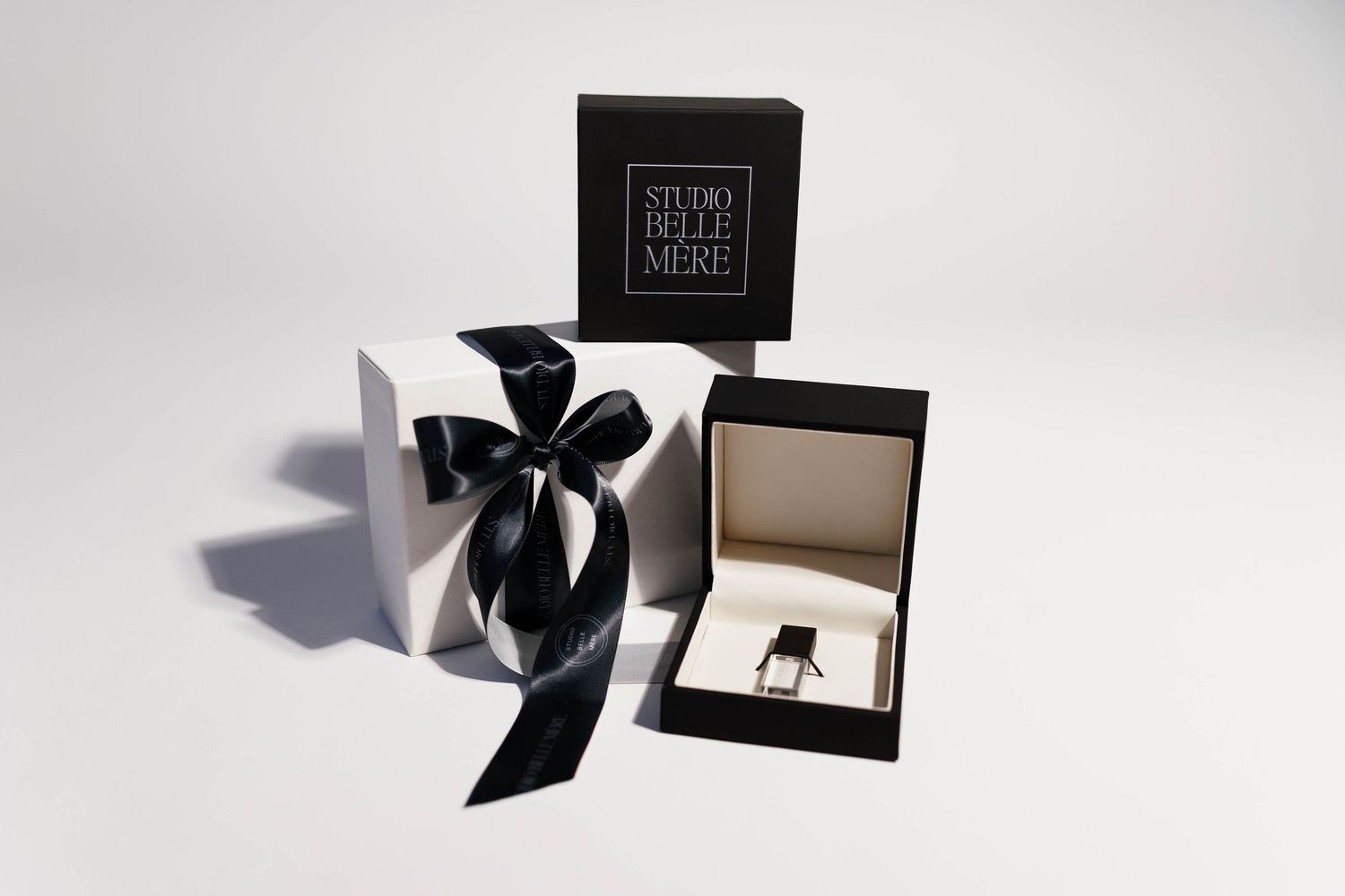 Modern product packaging with black bow and presentation box on white background.