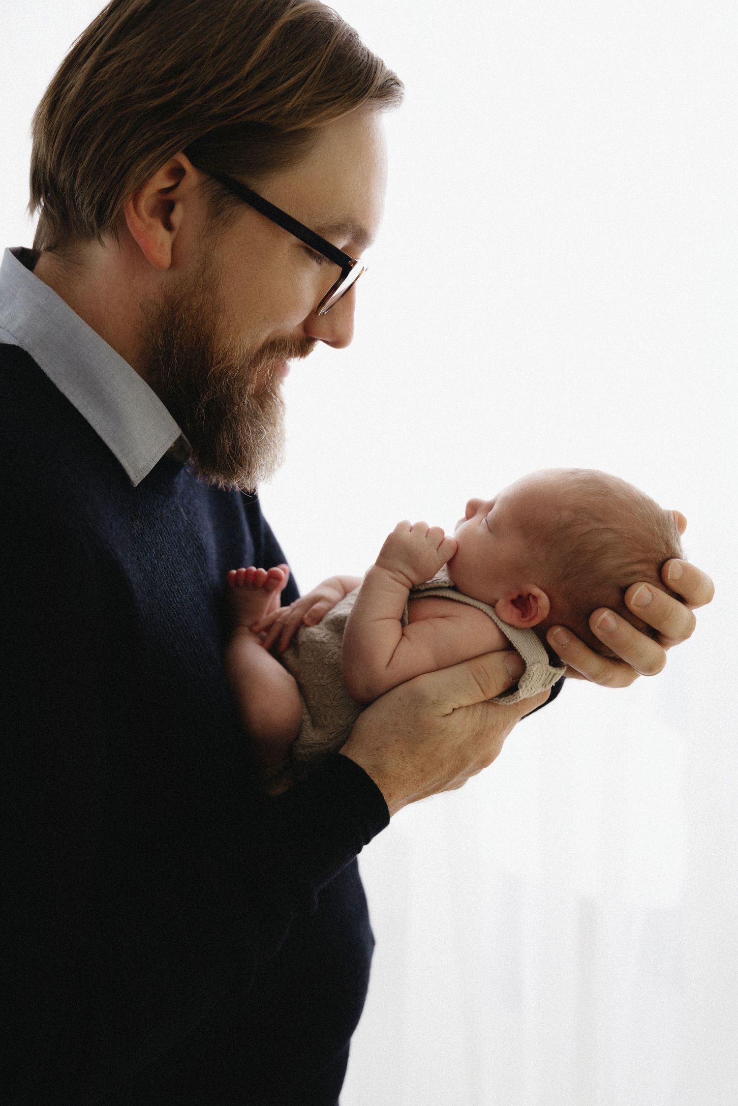 A sequence of tender moments showing a parent kissing and cradling their newborn baby against a white background.