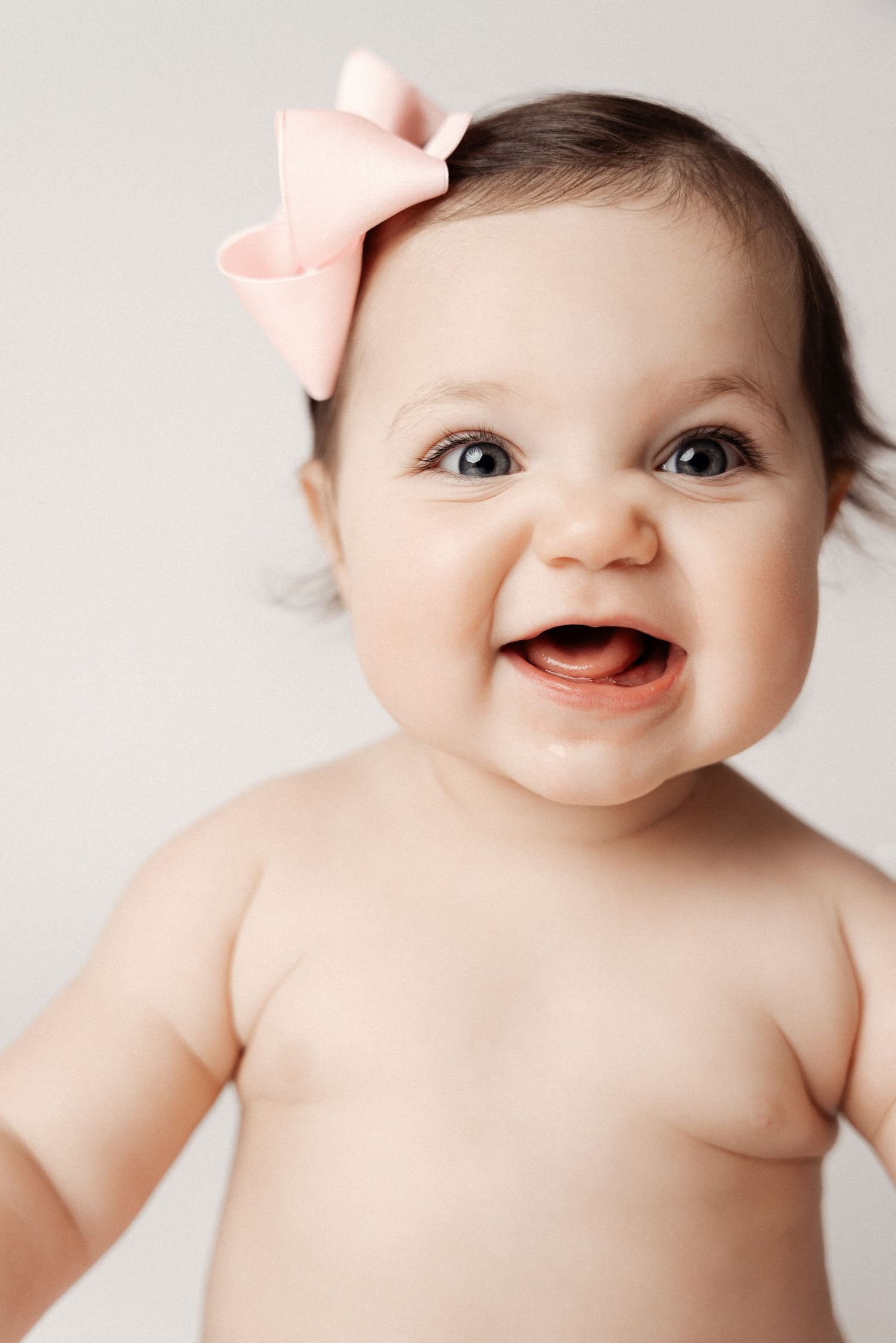 A series of four close-up photos showing a happy baby with a pink bow against a white background.