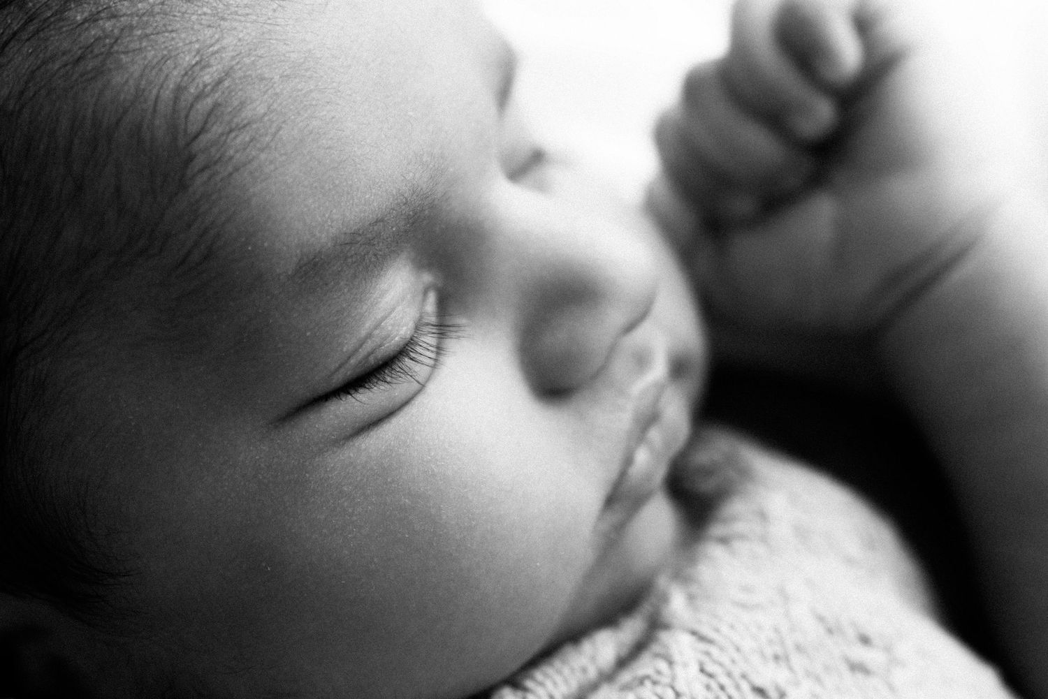 Close-up black and white photo of a sleeping infant's face showing peaceful expression and delicate features.