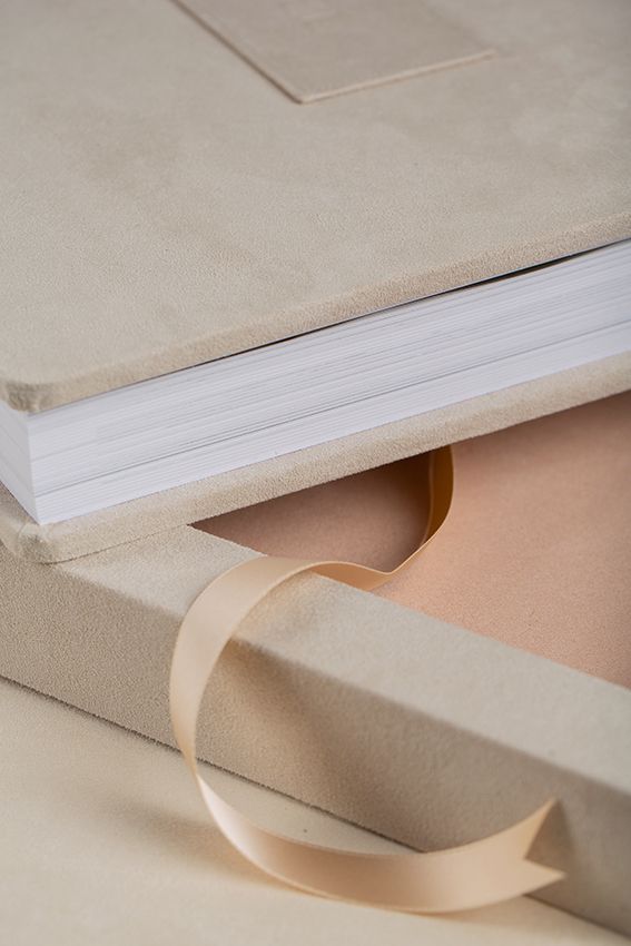 Close-up view of a white book page corner with a peach-colored ribbon bookmark against a light background.