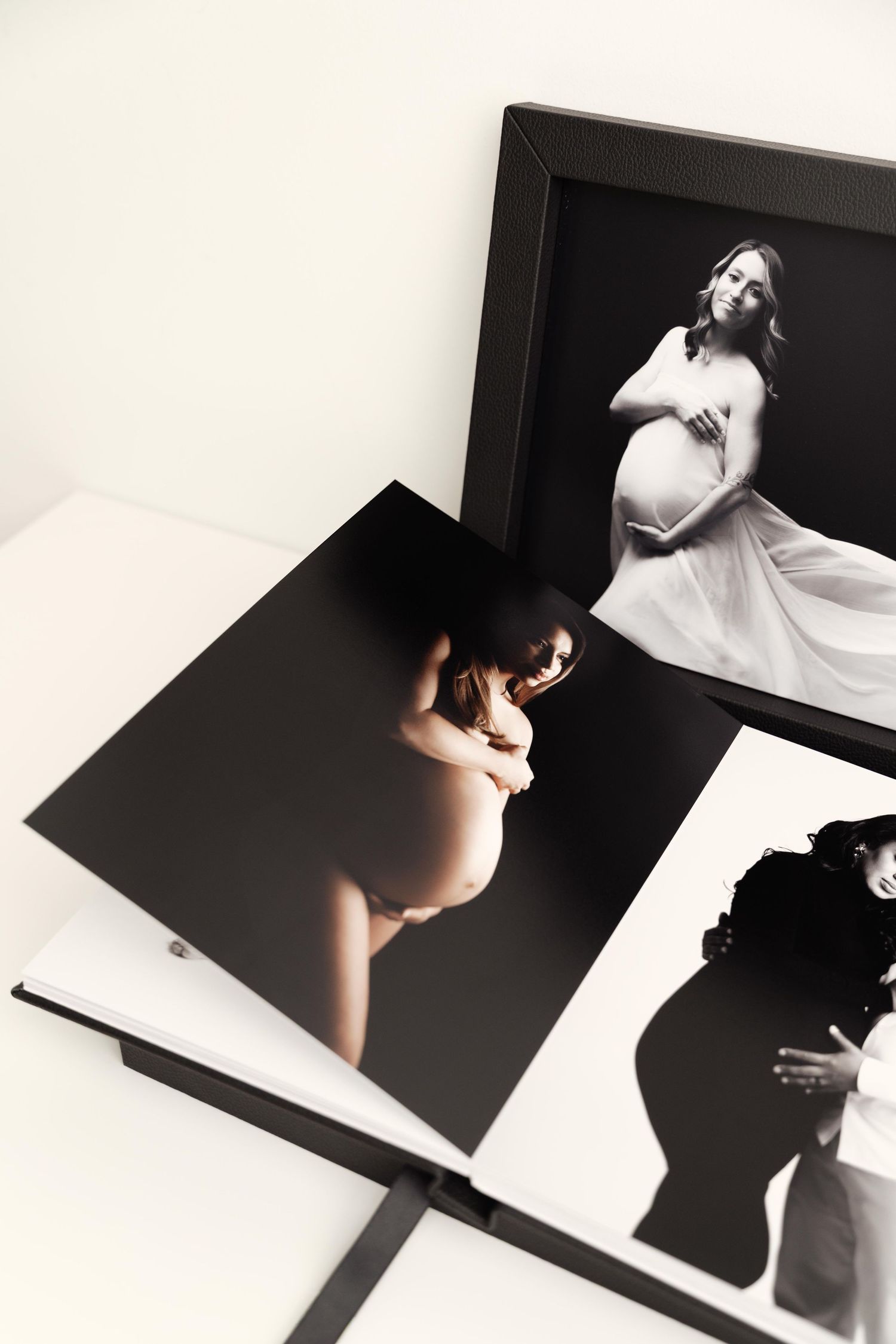 Black and white maternity photography prints displayed showing artistic silhouettes and poses.