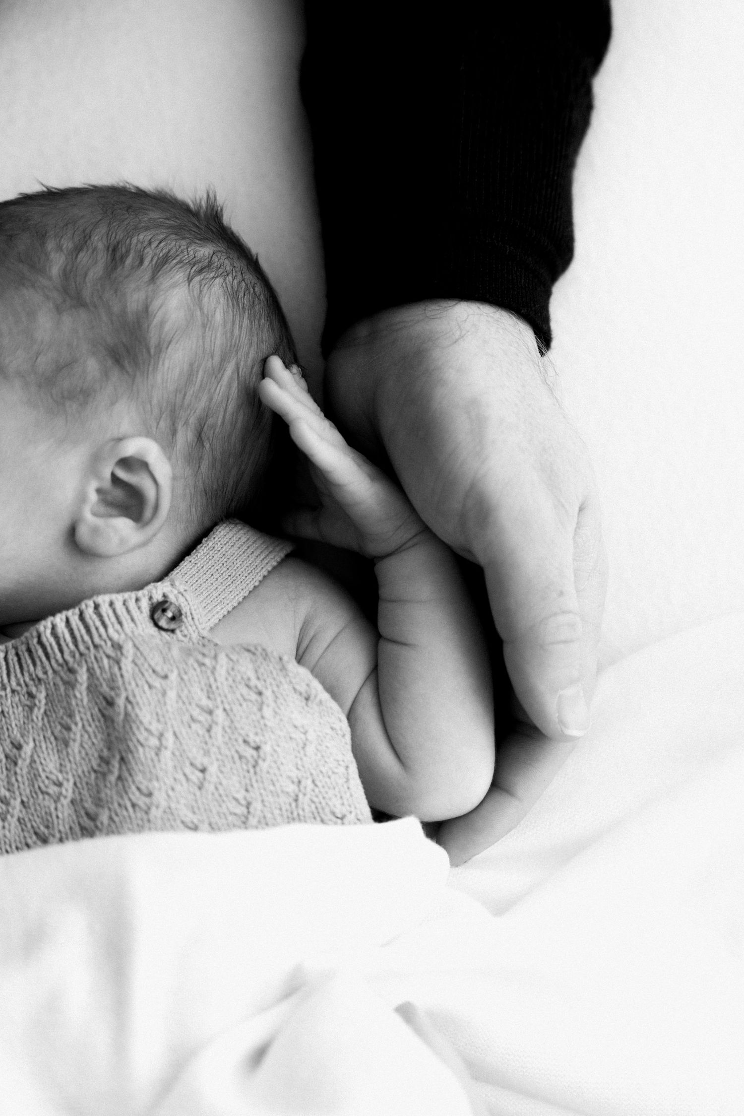 A tender black and white photograph shows a baby sleeping peacefully against soft white bedding.