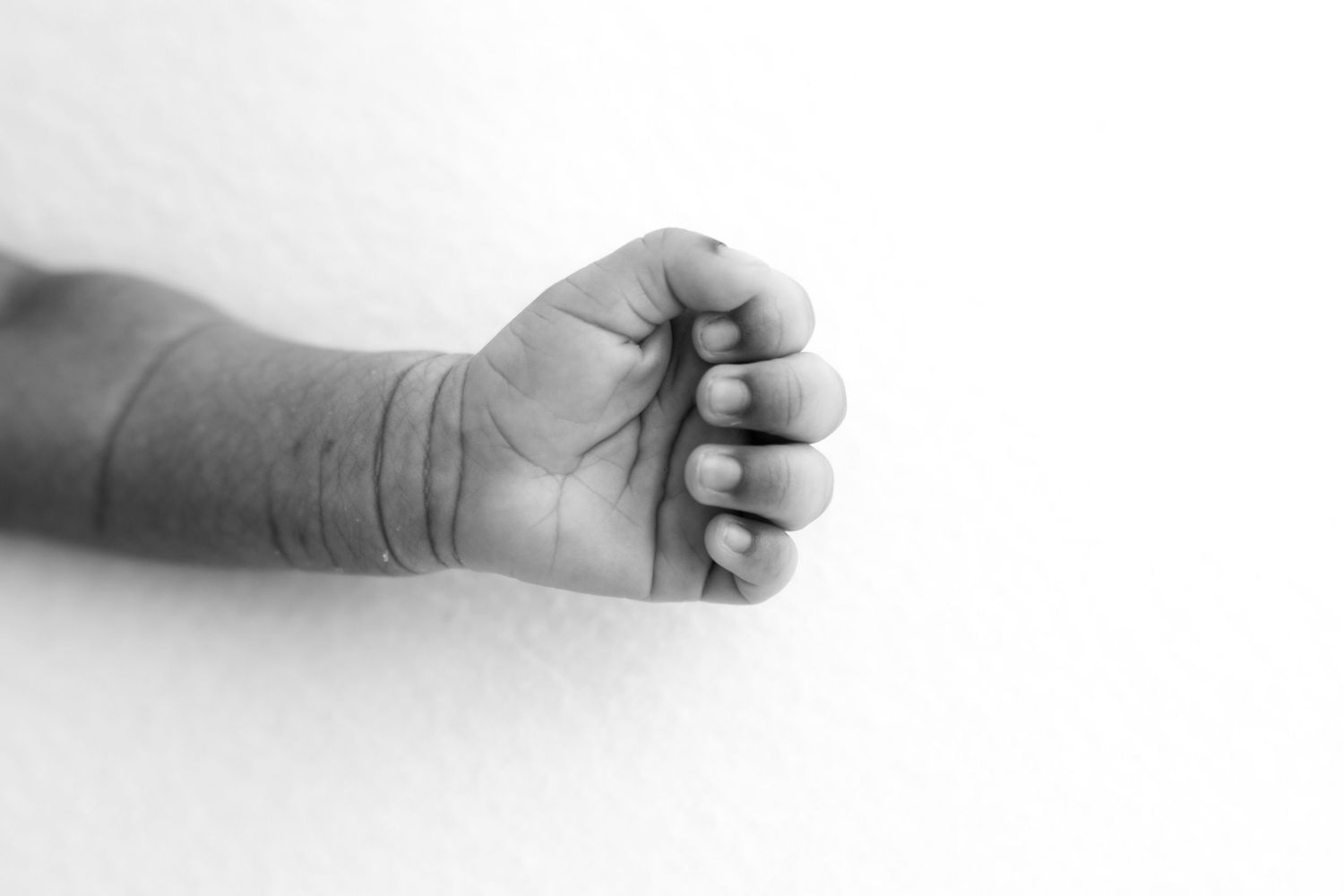 Artistic black and white image showing a series of baby hands reaching across the frame.