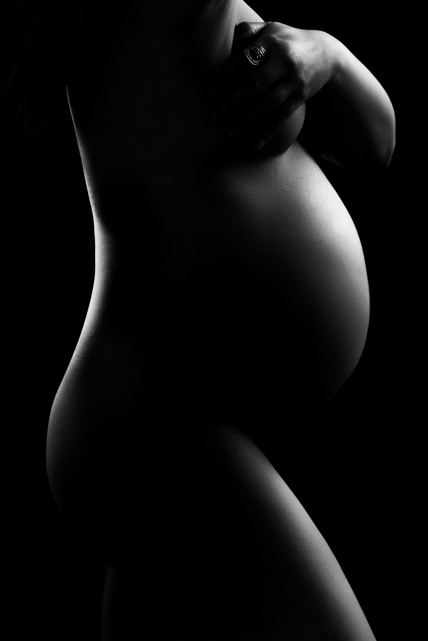 A series of black and white artistic photographs showing silhouettes of a pregnant woman's belly in different angles.