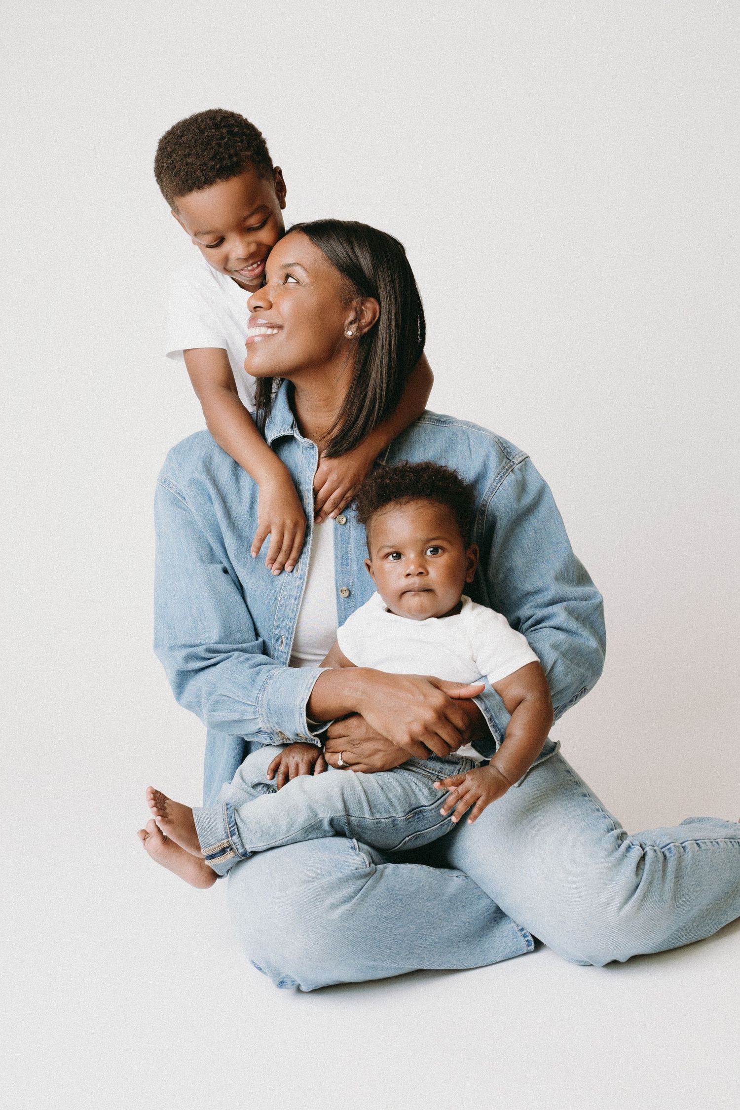 A tender moment captured in a minimalist studio setting showing affectionate interaction in matching light blue outfits.