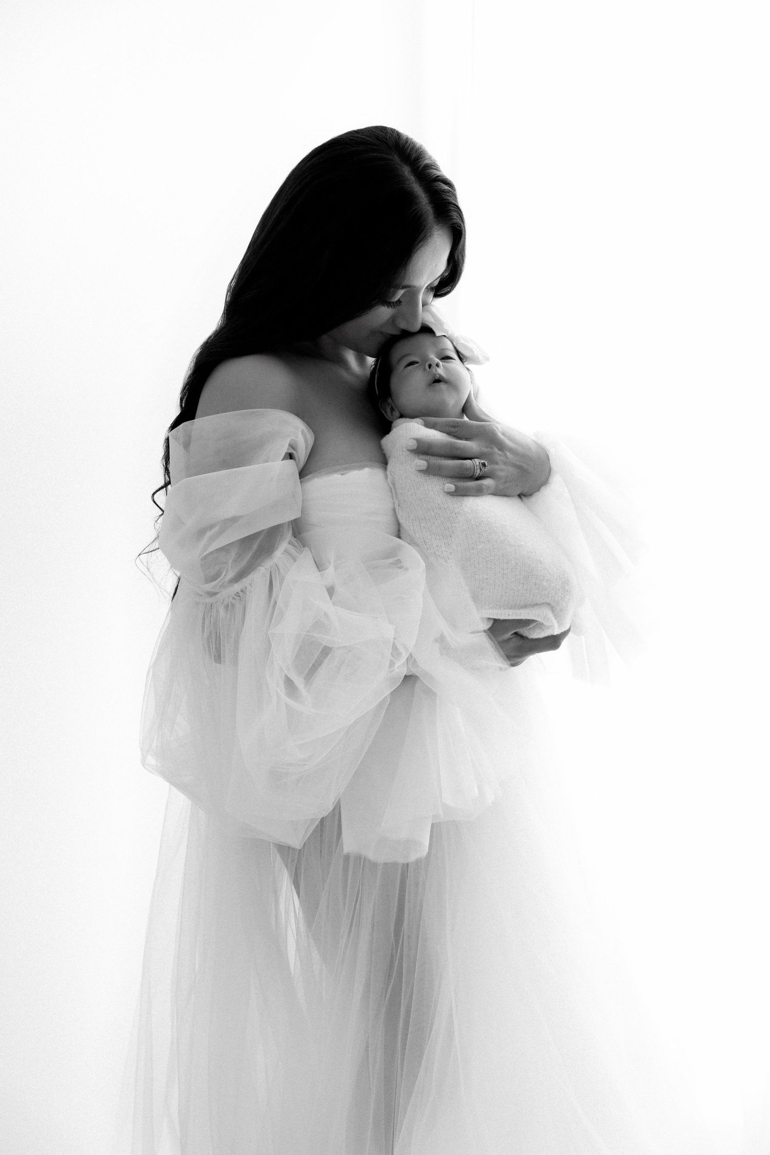 A series of ethereal black and white photos showing intimate embraces between figures in flowing white garments.