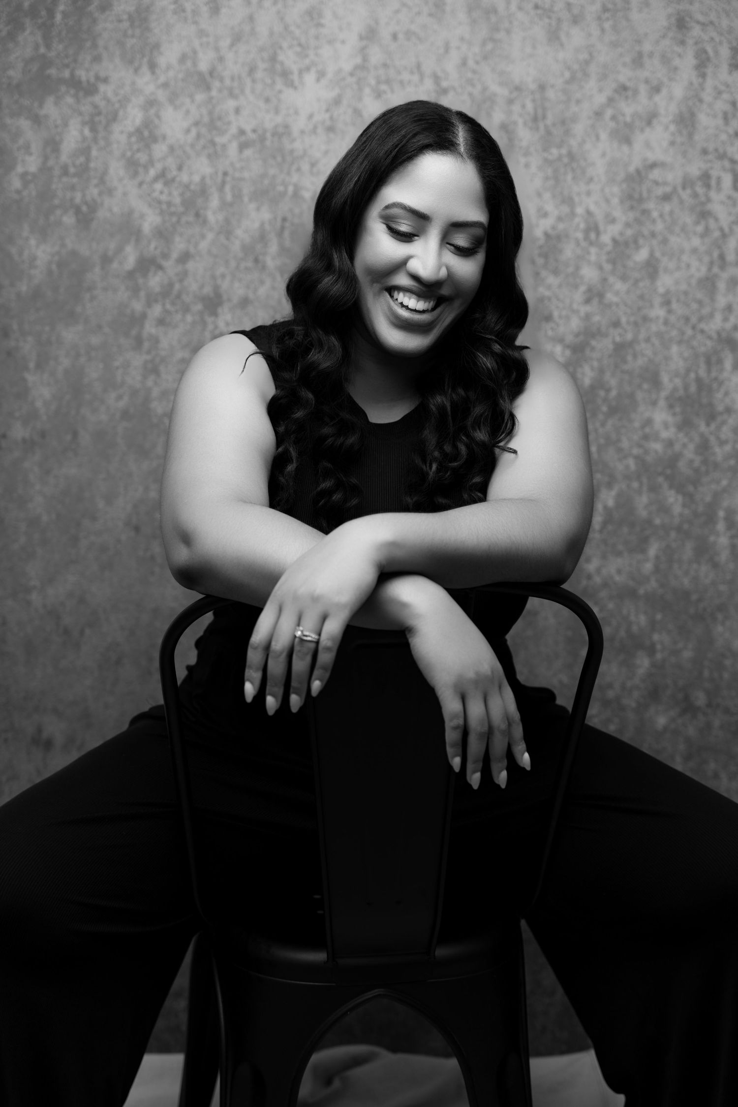 Artistic black and white portraits featuring relaxed poses on a chair with a textured backdrop.