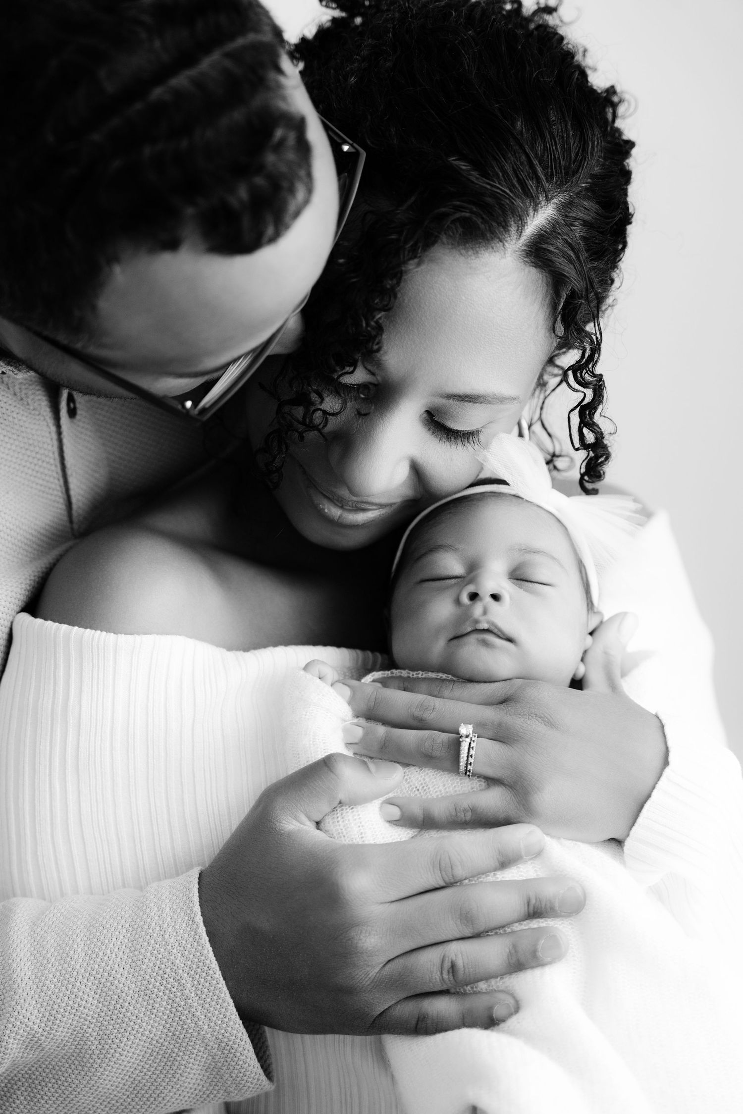 Artistic black and white portrait series capturing tender moments between parent and newborn.