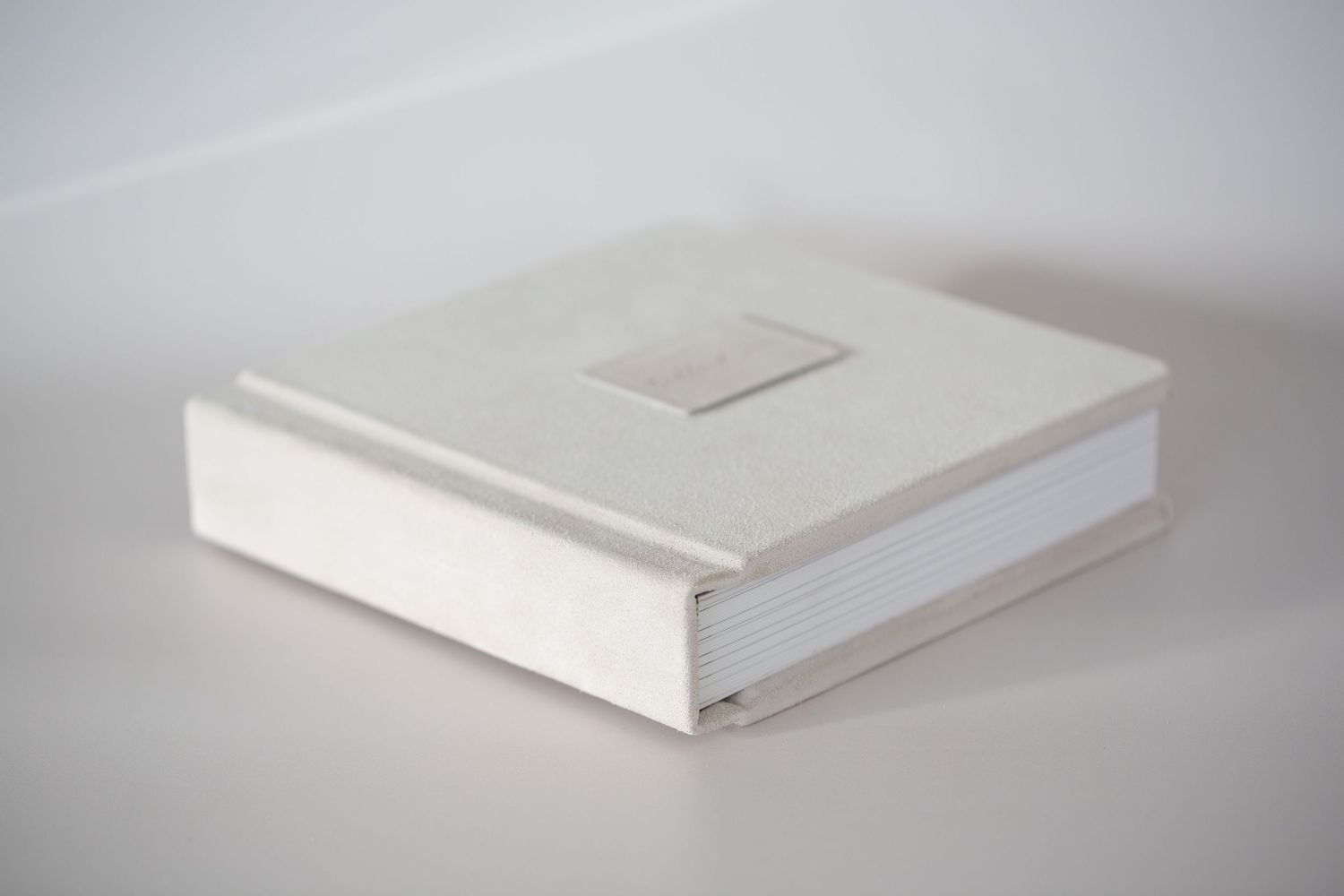 A white hardcover book shown at different angles on a light background demonstrates its shape and construction.
