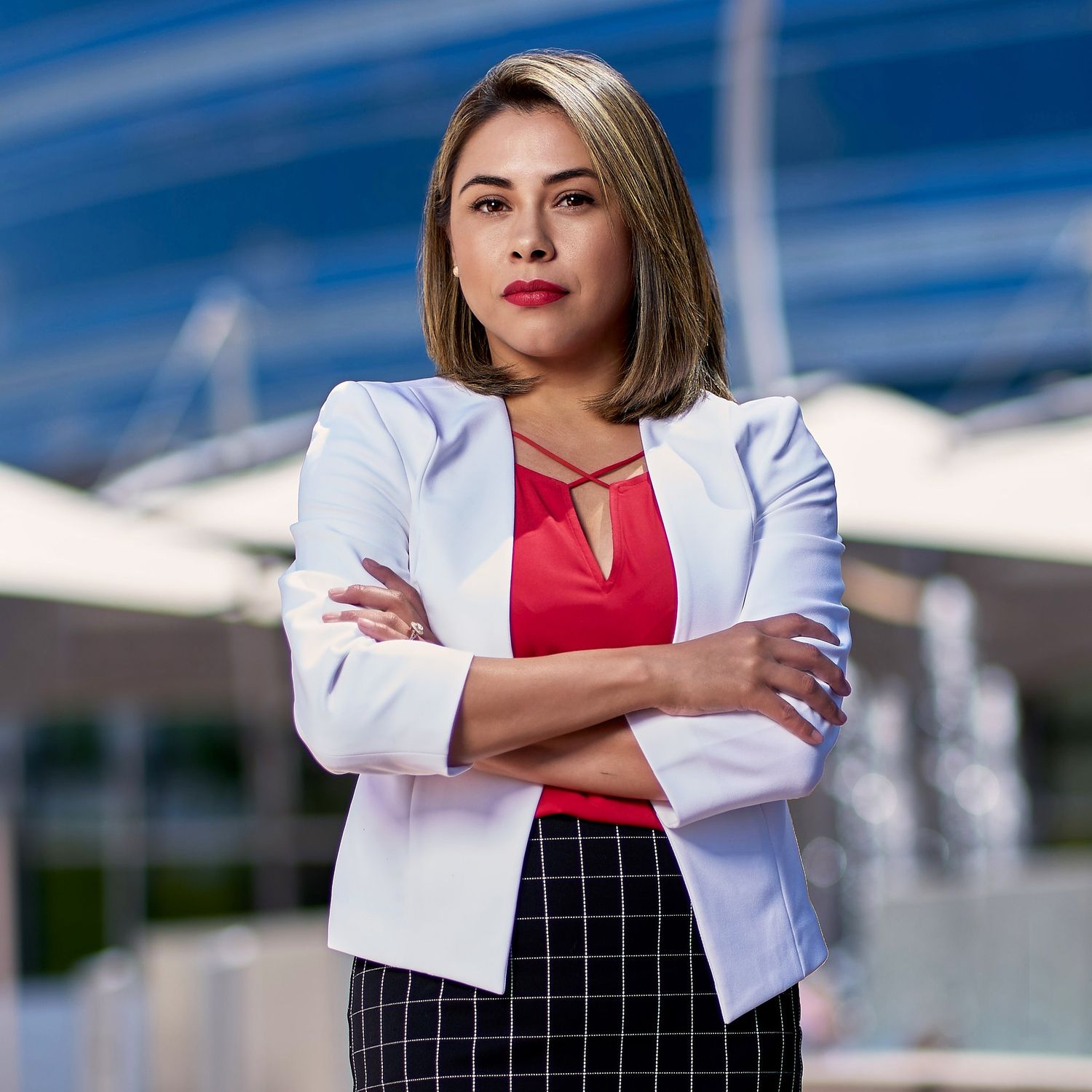 Professional woman in business attire poses confidently against blurred urban background. Photographer RL Davis
