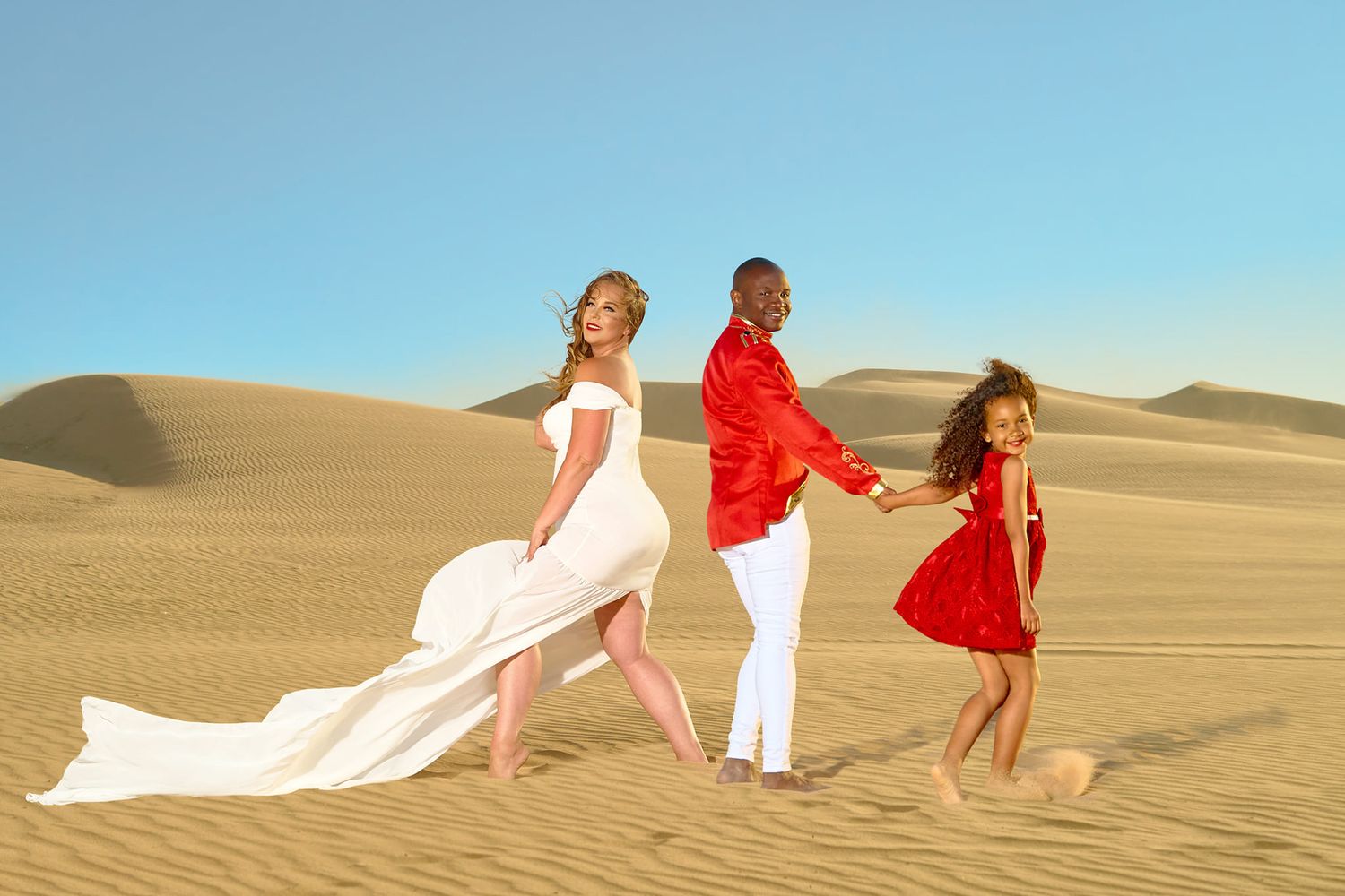 People in white and red outfits create artistic poses on sandy desert dunes. Photographer RL Davis