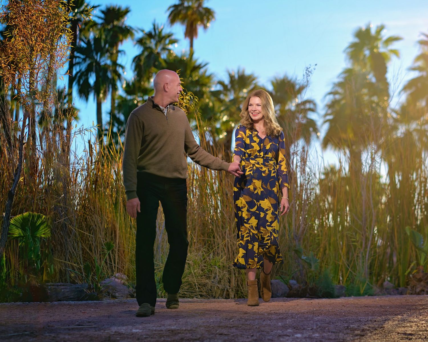 A couple poses together at sunset among palm trees in a romantic setting. Photographer RL Davis