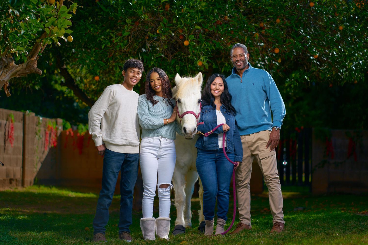 Family gathering for outdoor portrait session near horse in garden setting. Photographer RL Davis