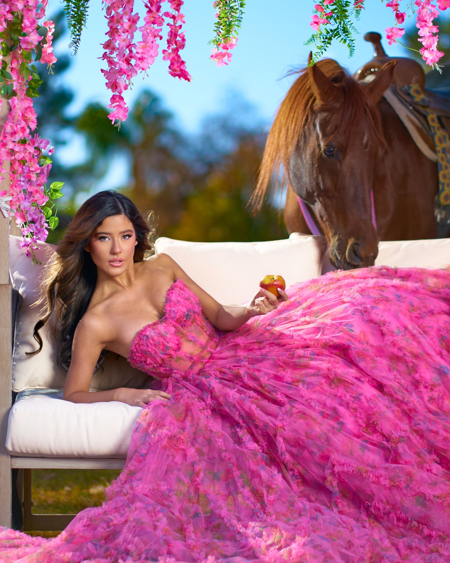 Flowing pink ballgown dress with ruffles photographed in an outdoor setting with hanging floral decorations. Photographer RL Davis