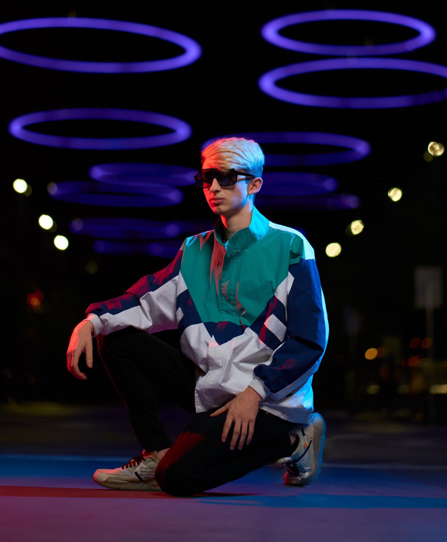Dancer in teal shirt performs against dark background with illuminated blue circles. Photographer RL Davis