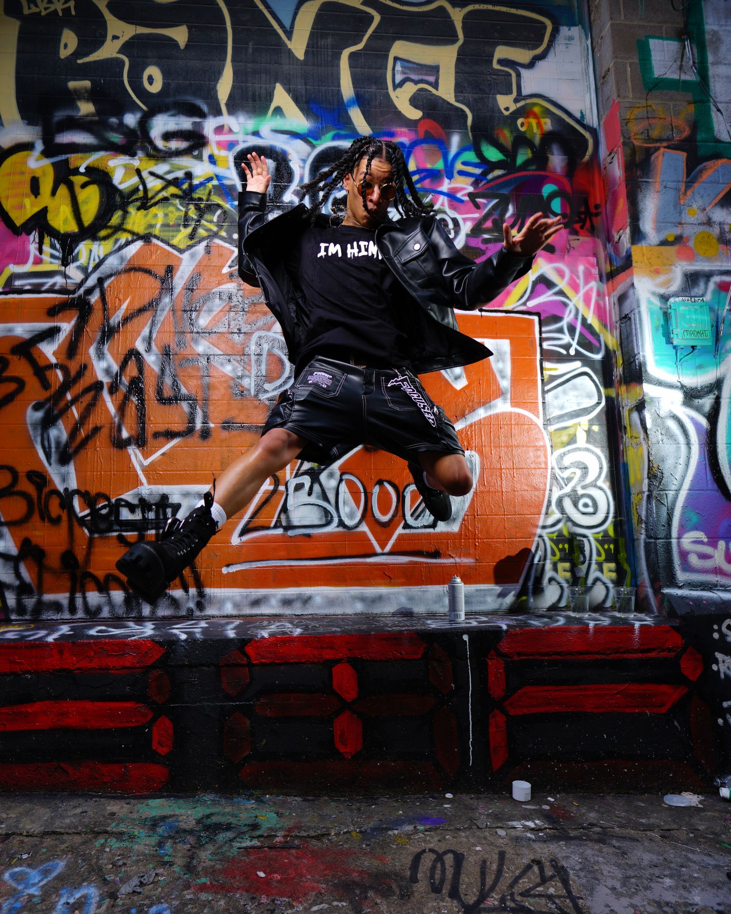 Dynamic dance pose silhouetted against colorful graffiti wall background. Photographer RL Davis