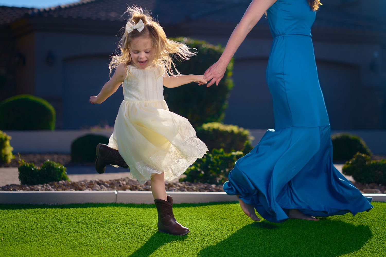 Young girl in white dress leaping joyfully in outdoor setting with blue sky background. Photographer RL Davis