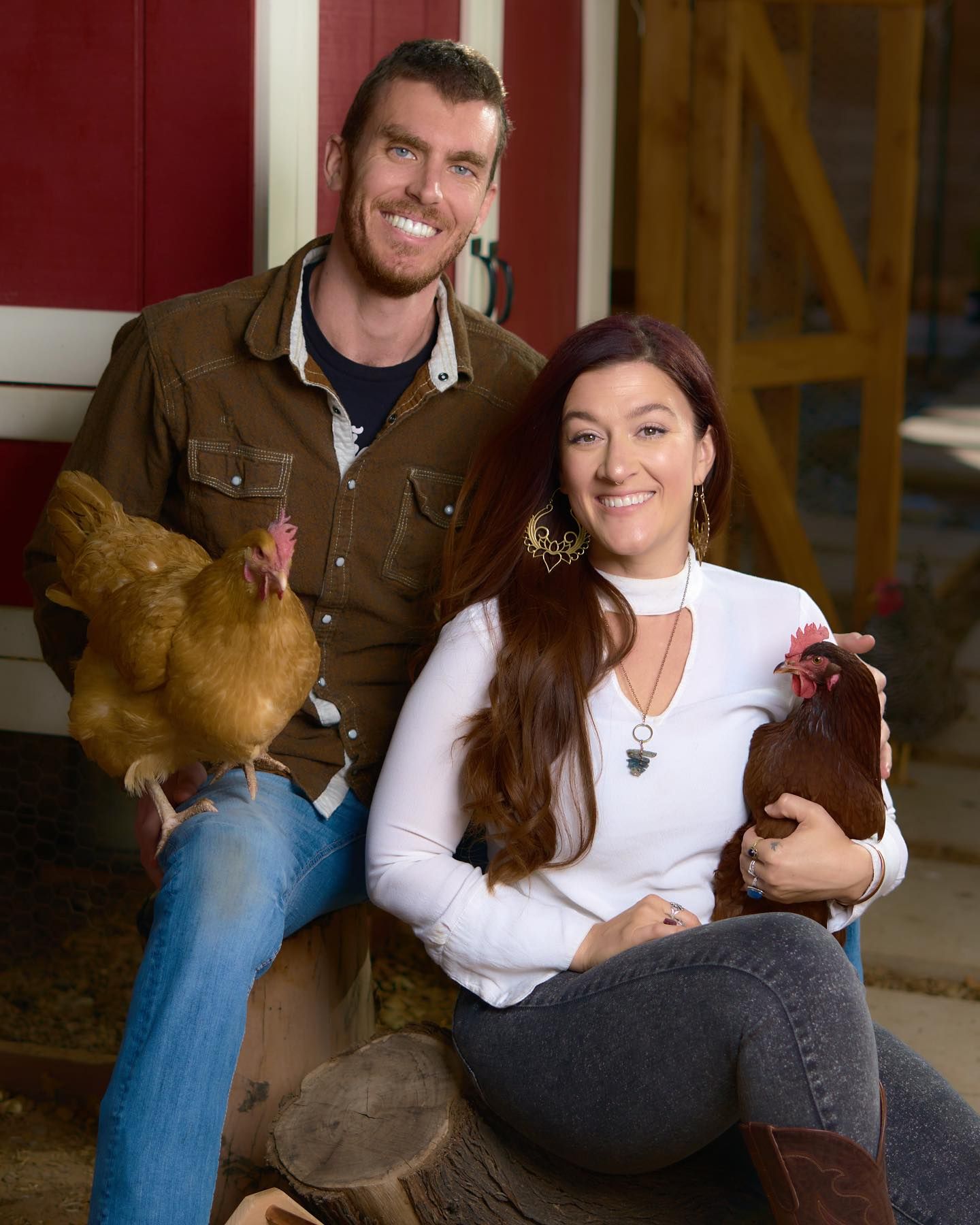 Couple sitting casually with chickens in rustic barn setting. Photographer RL Davis