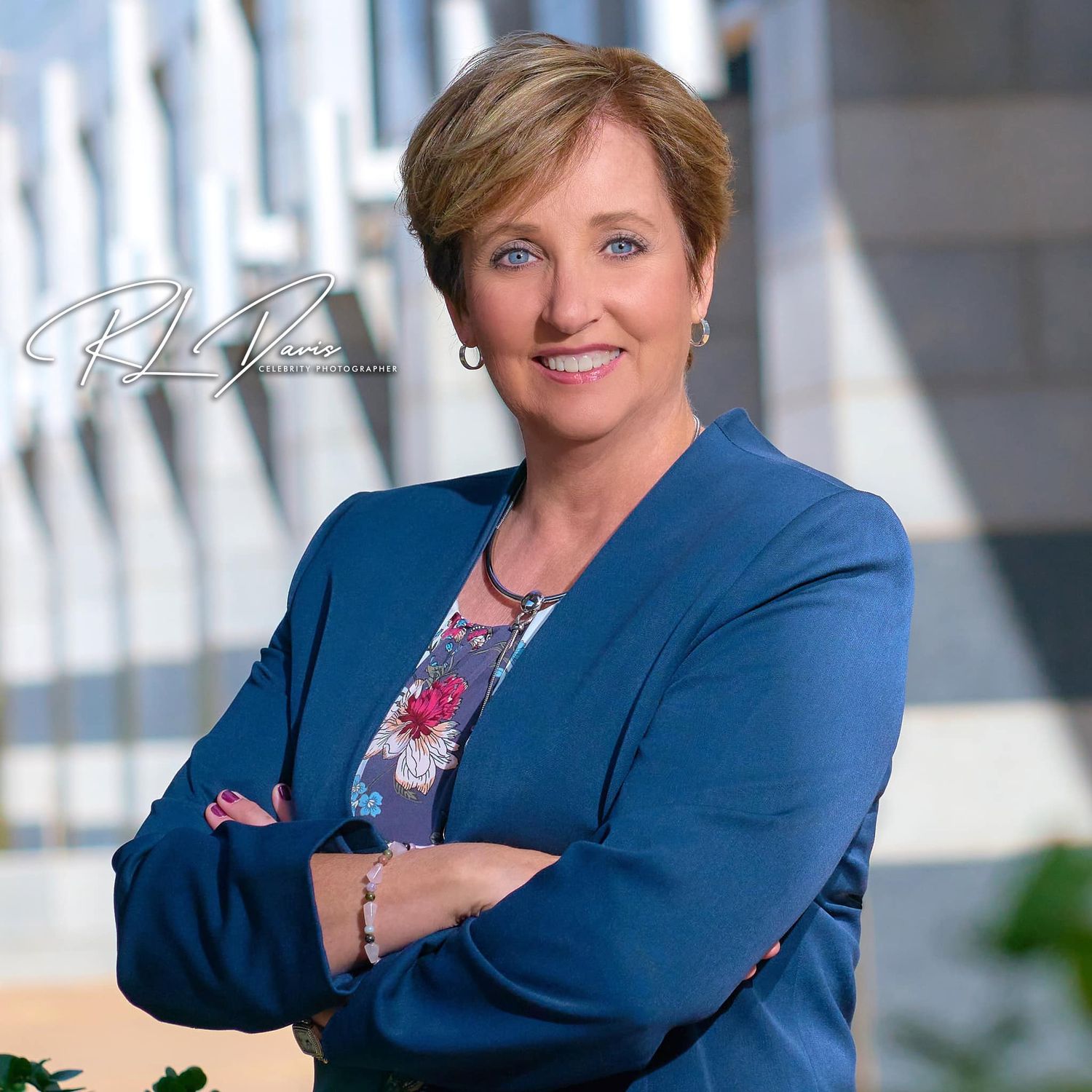 Executive portrait in blue blazer against modern architectural background. Photographer RL Davis