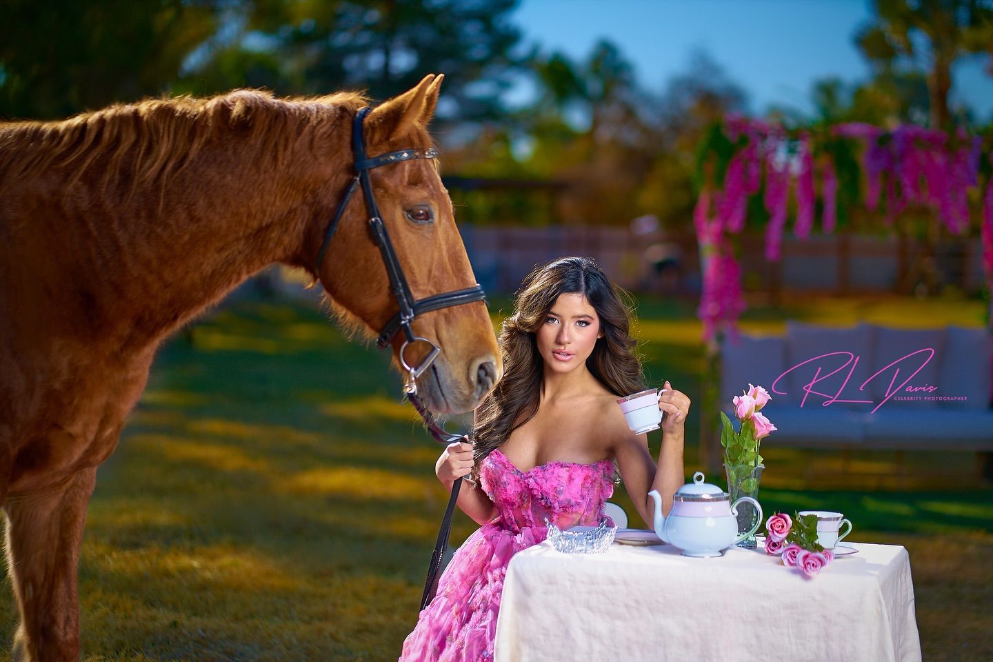 Elegant tea party setup with horse and floral decorations outdoors. Photographer RL Davis