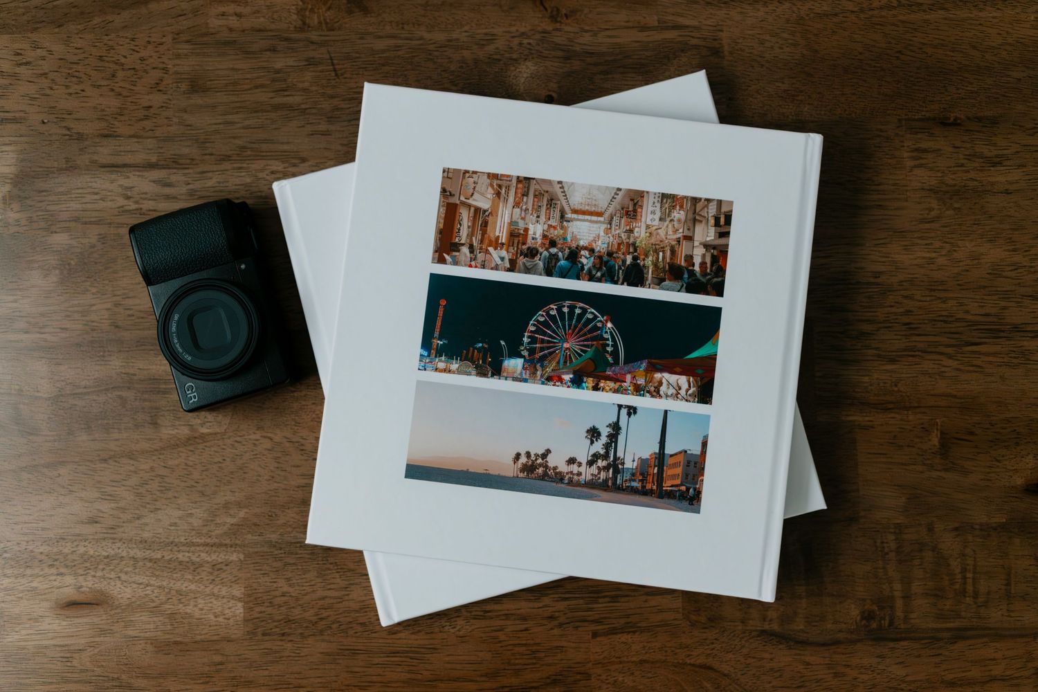 Photo album with travel photos of a ferris wheel and cityscape beside a vintage camera on a wooden table.