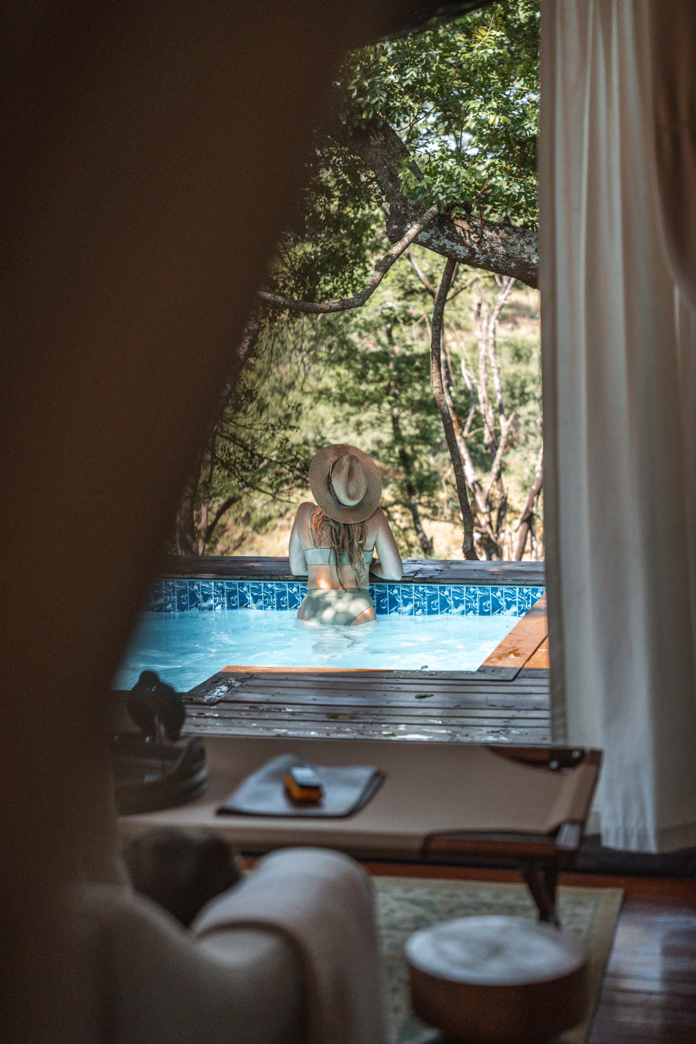 Poolside view through curtains at luxury safari lodge with blue mosaic tile.