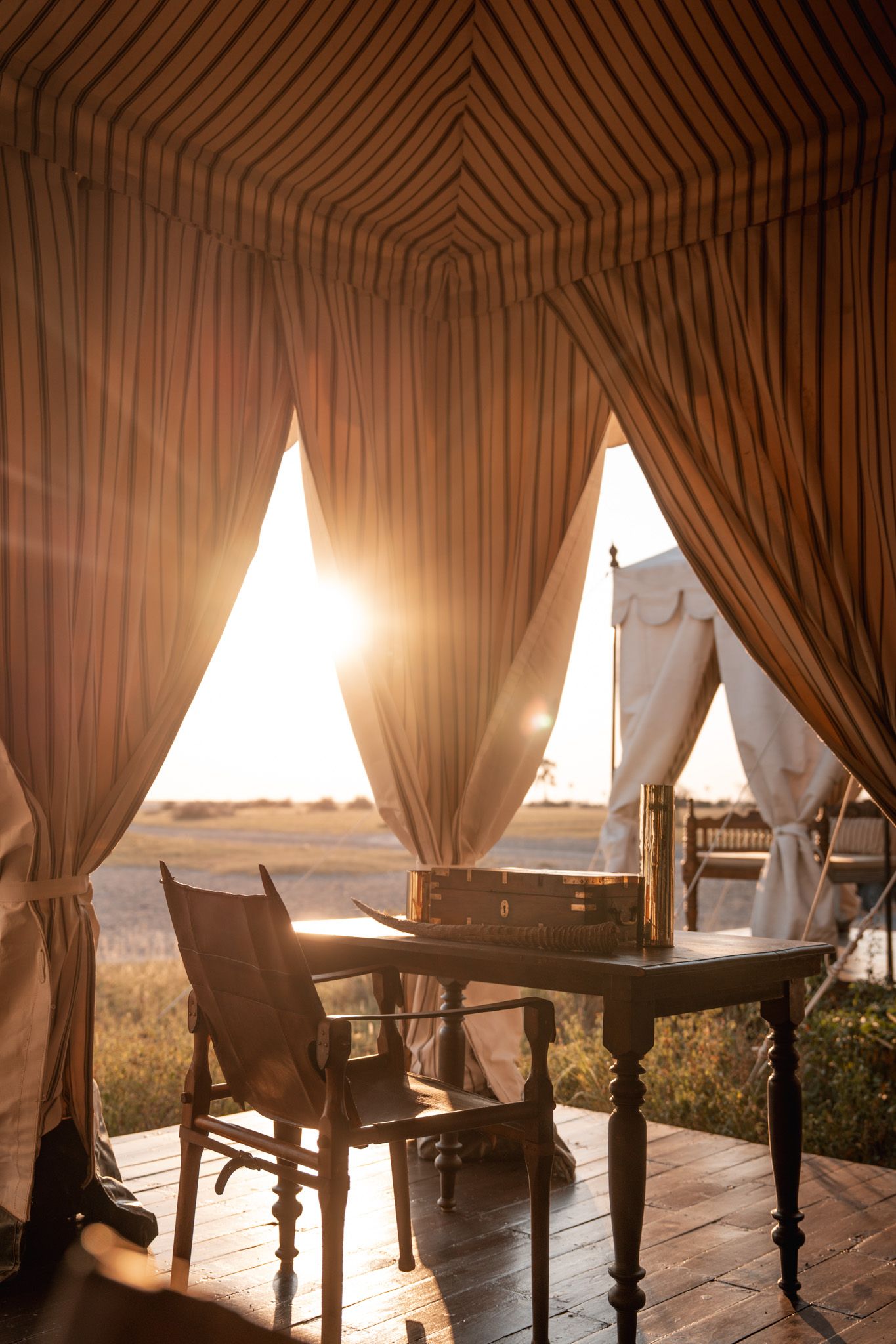 Sunlight streams through elegant drapes and curtains in a rustic dining area.