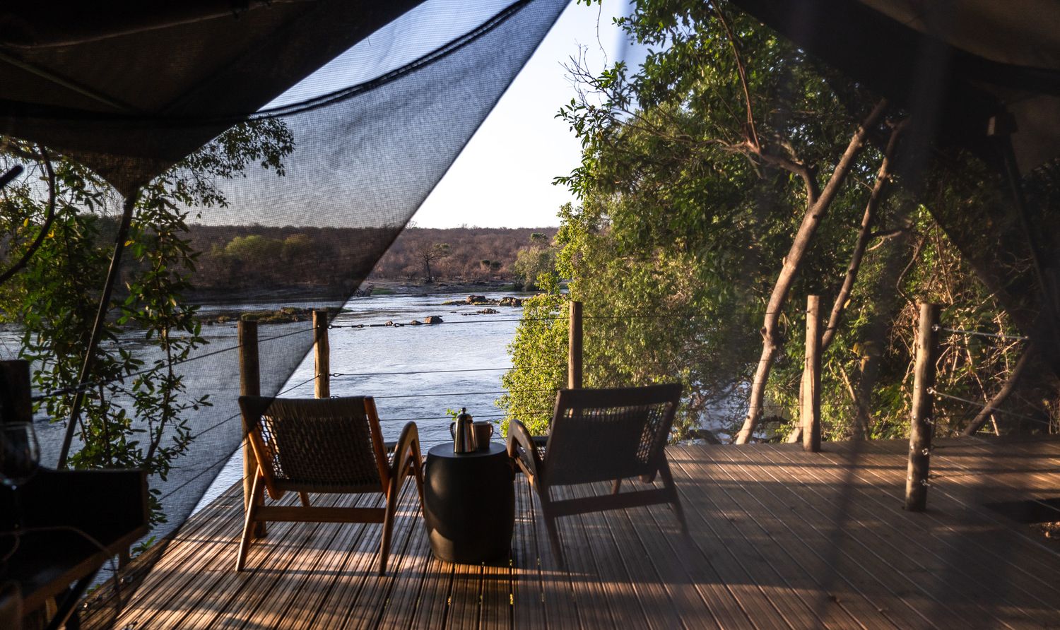 Wooden deck terrace overlooking water during sunset with dramatic silhouette views.