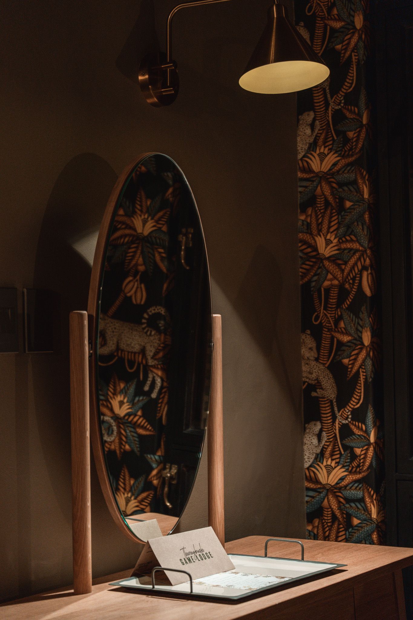 Elegant vanity area with butterfly wallpaper, round mirror, and pendant lighting creating dramatic shadows.